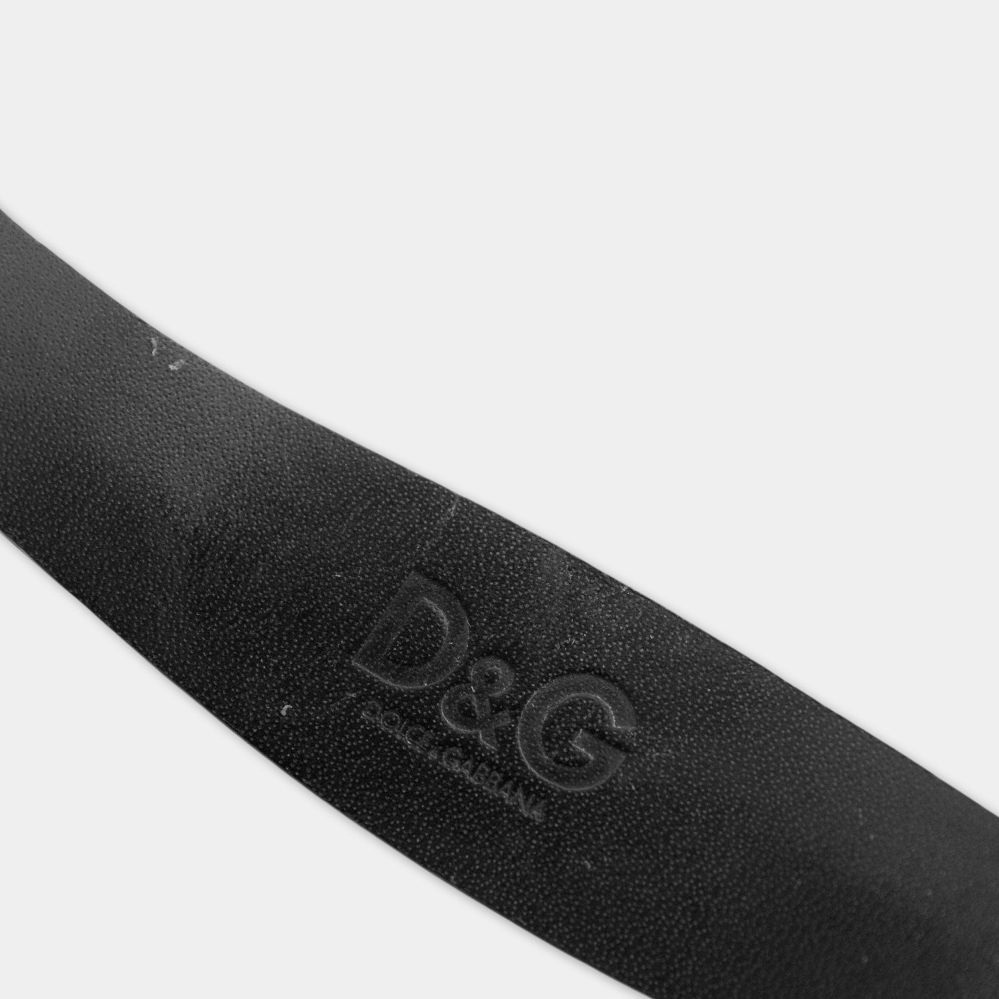 A close-up view of a black leather belt with the D&G logo embossed on it.