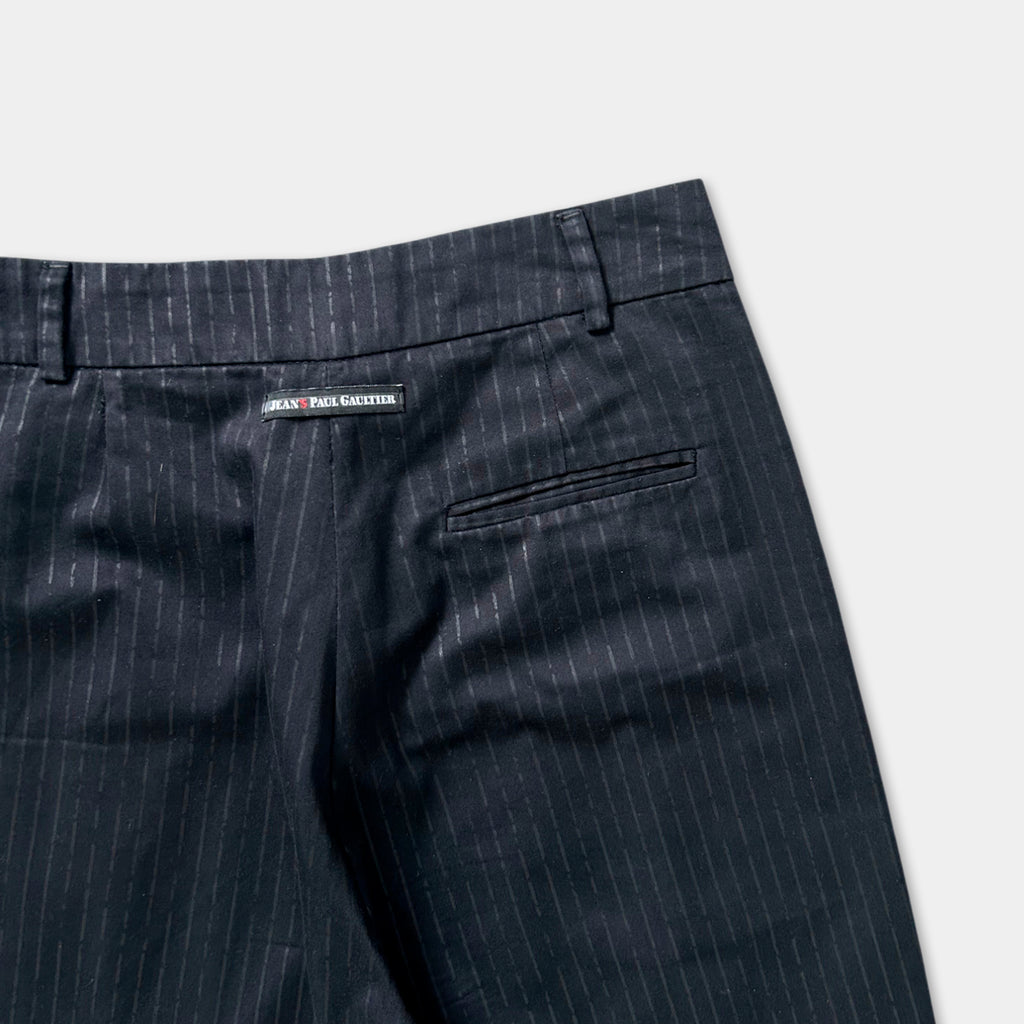 A pair of black pinstriped trousers with a label on the waistband.