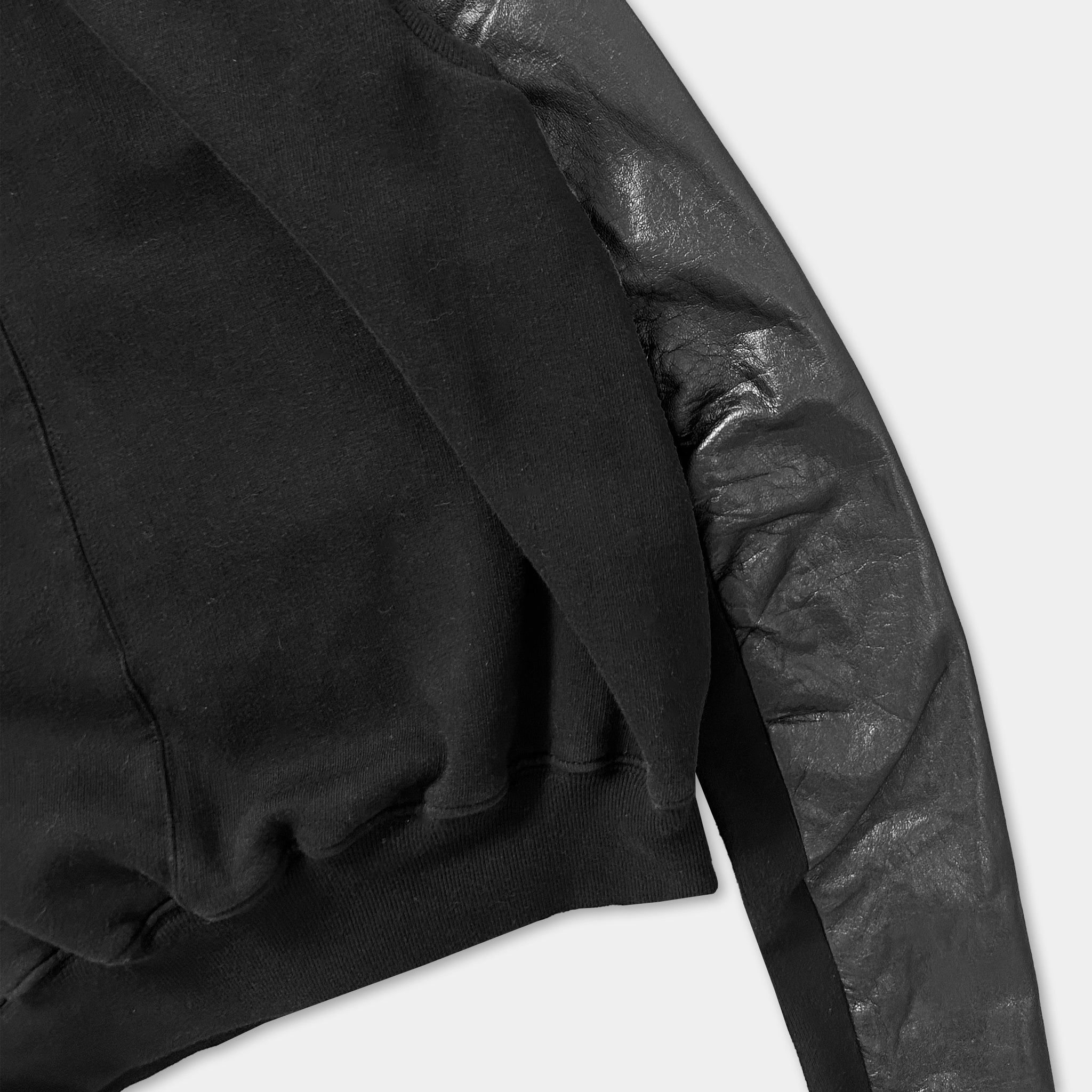 A close-up view of a black hoodie with a shiny, textured sleeve.