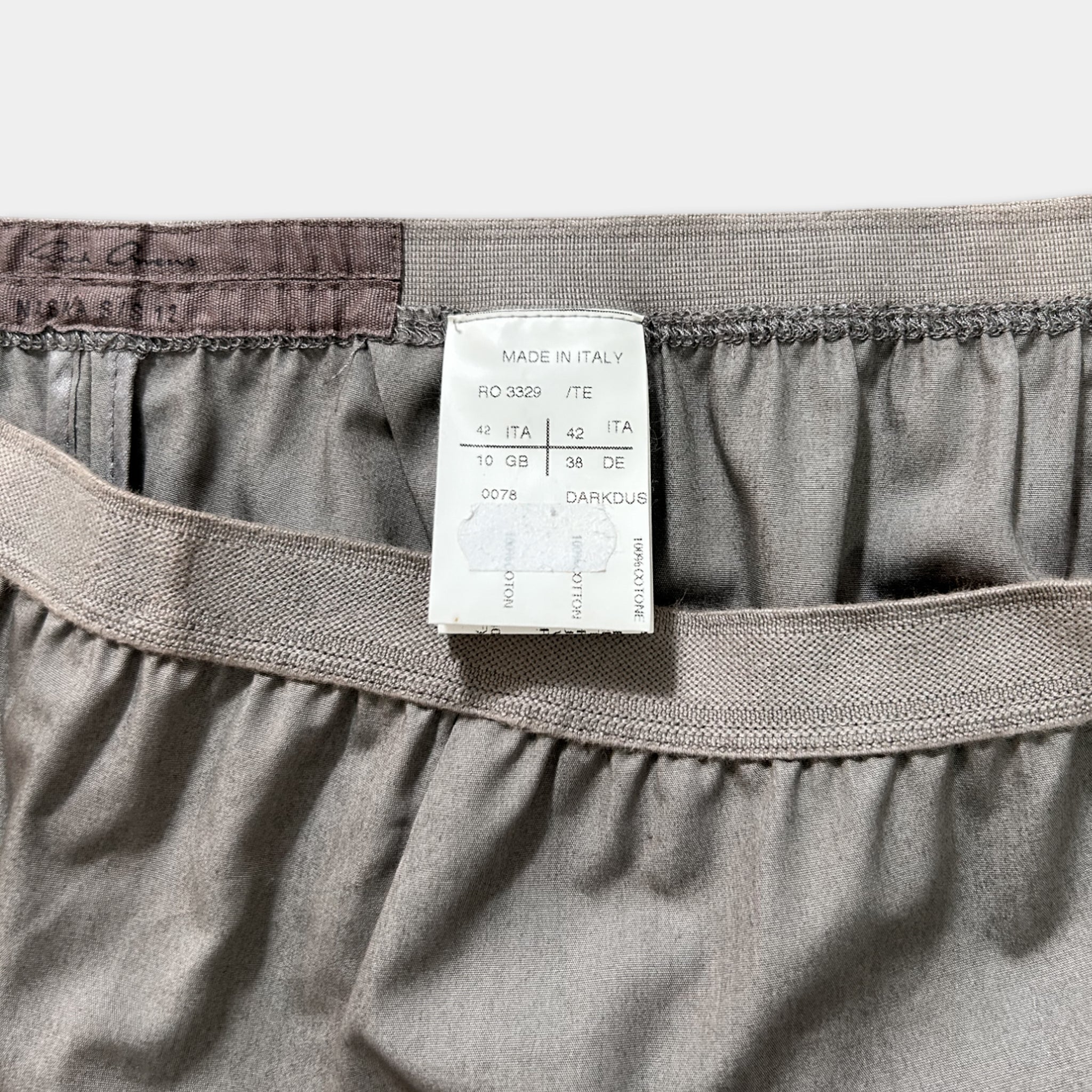a close-up view of a gray fabric, possibly a piece of clothing, with a label attached to it. The label appears to be a description or information about the fabric, such as its material, origin, or production details.
