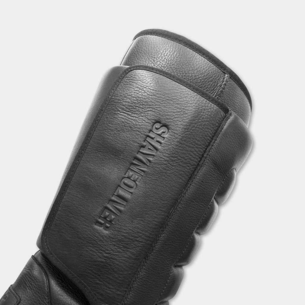 A close-up view of a black leather glove with embossed text on it.