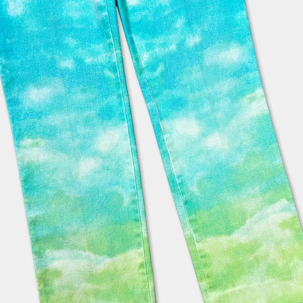 A pair of blue jeans with a cloud-like pattern painted on the fabric.