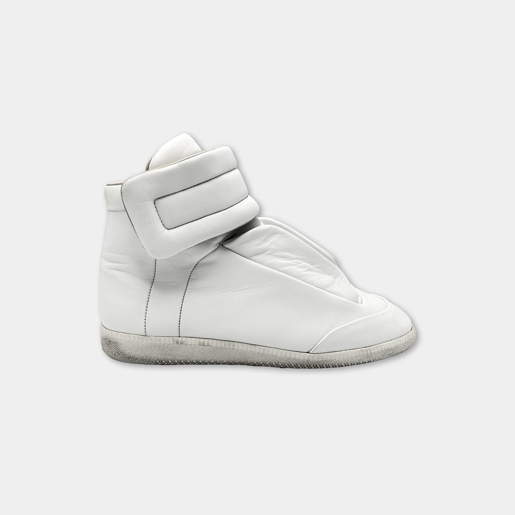 A white high-top sneaker with a strap on the side.