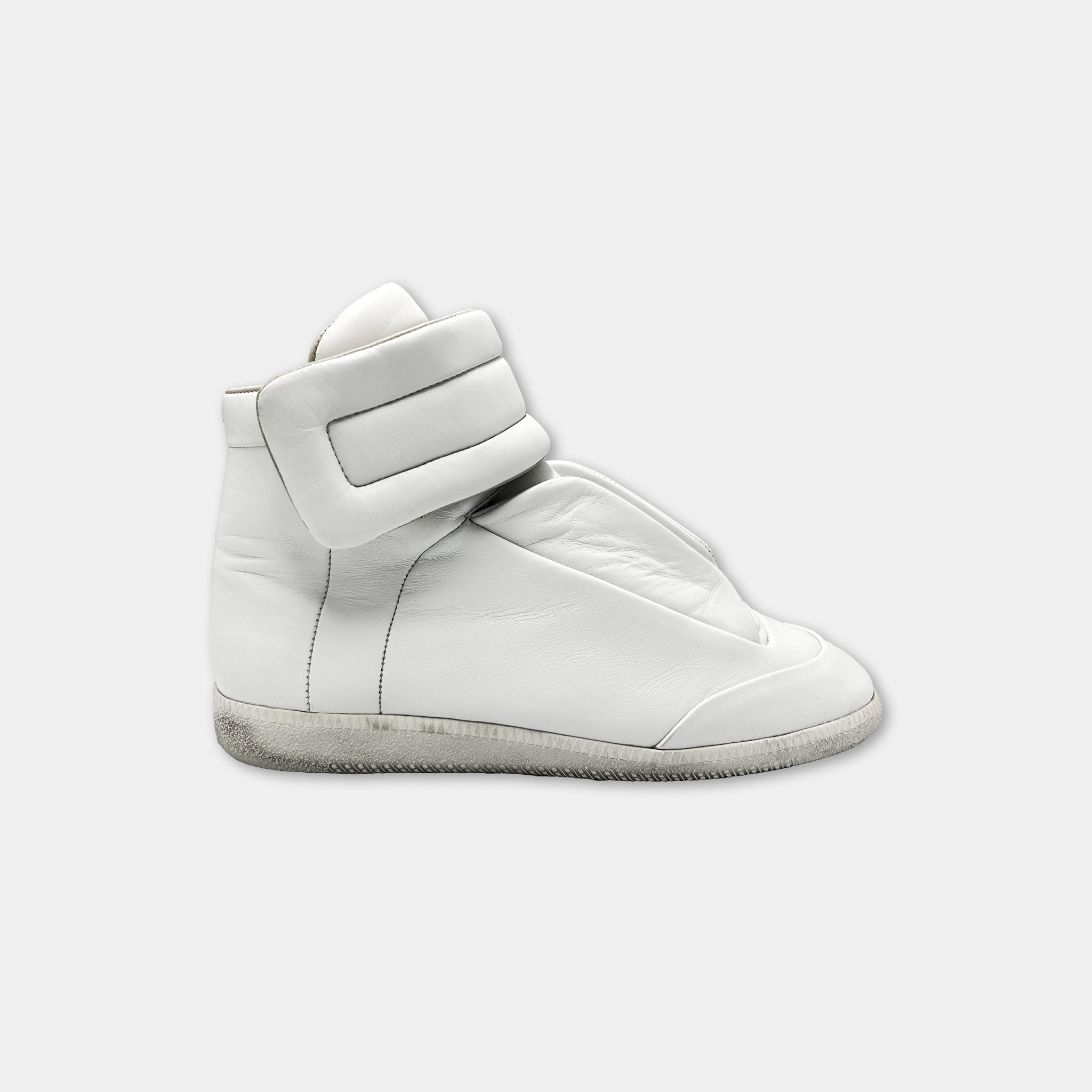 A white high-top sneaker with a strap on the side.