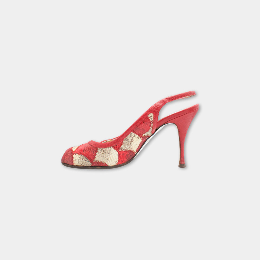 A red high-heeled shoe with a patterned design on the toe and heel.