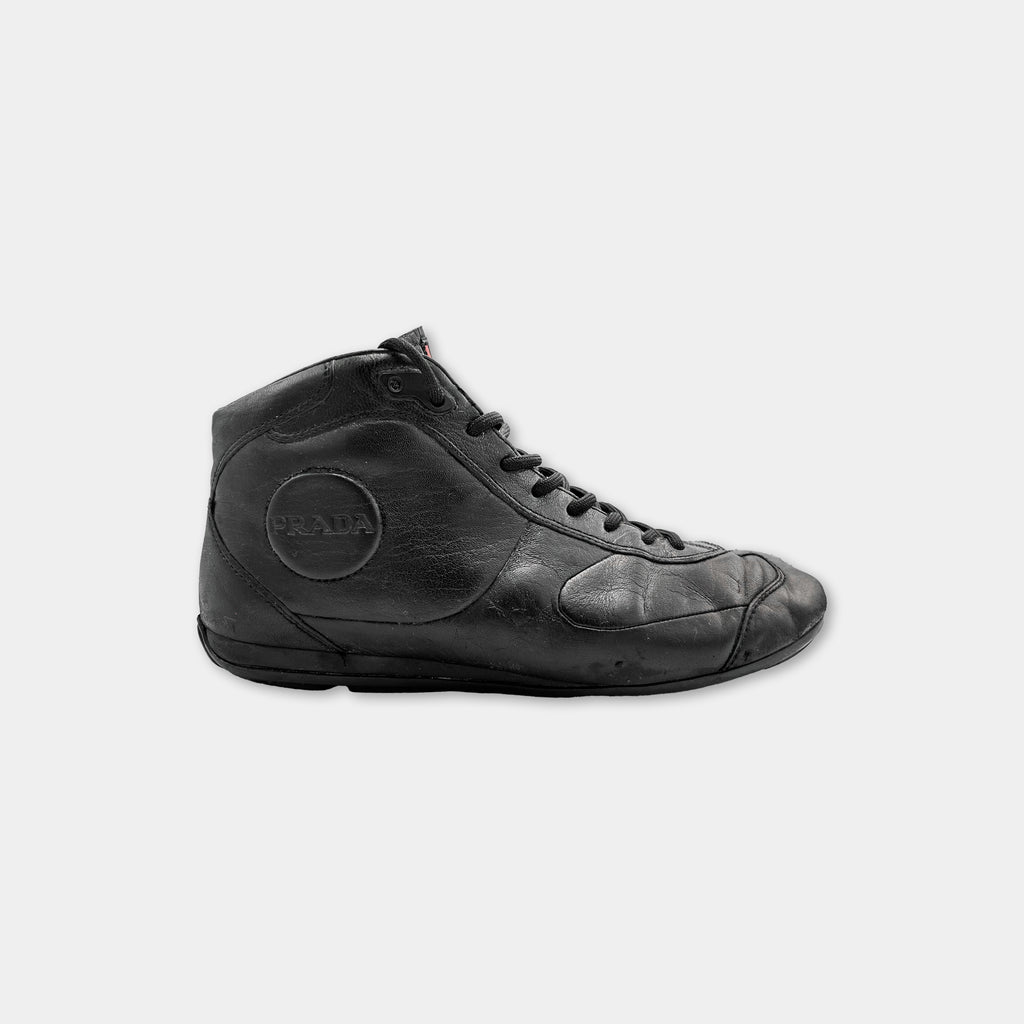 A black leather sneaker with a round logo on the side.