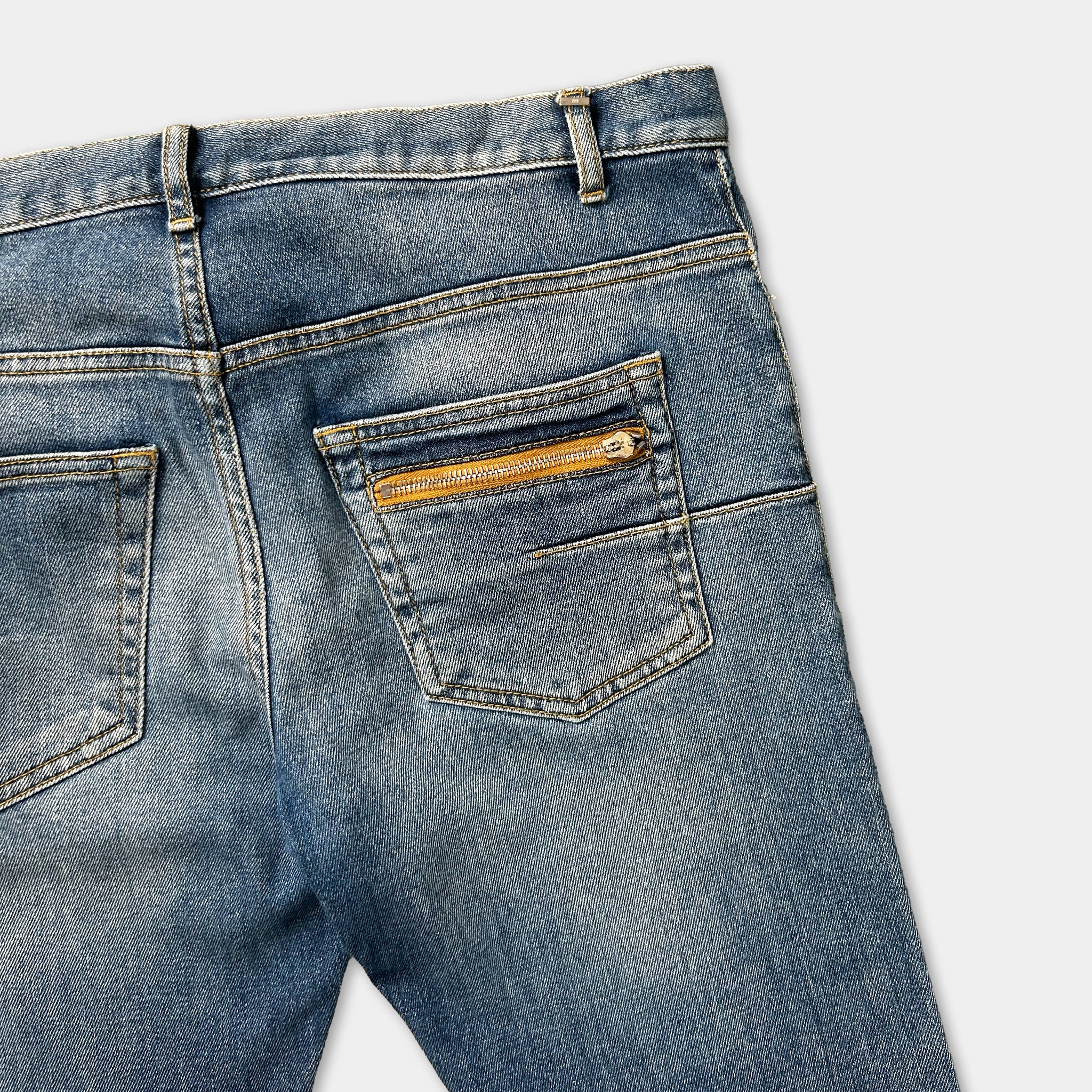 A pair of blue jeans with a zipper pocket and a gold zipper pull.