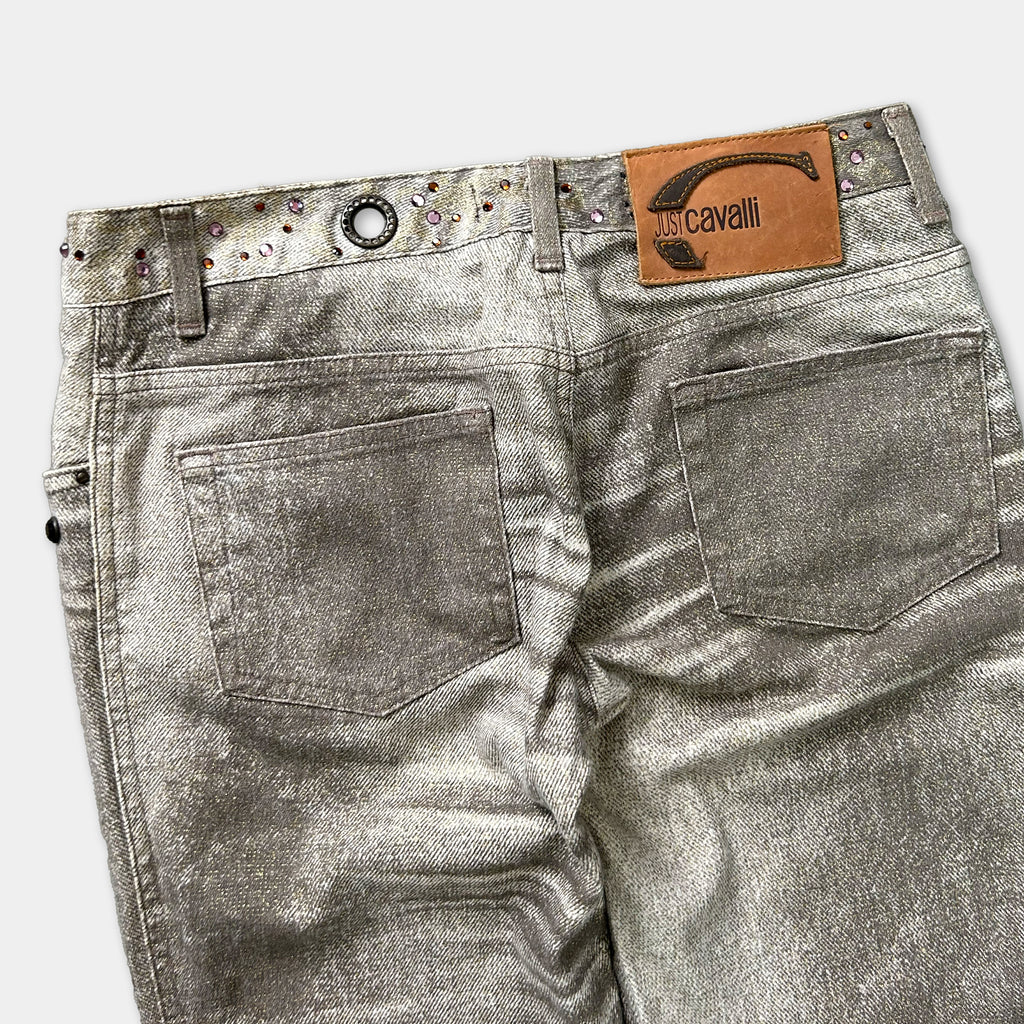 A pair of shiny silver jeans with a leather patch on the back pocket.