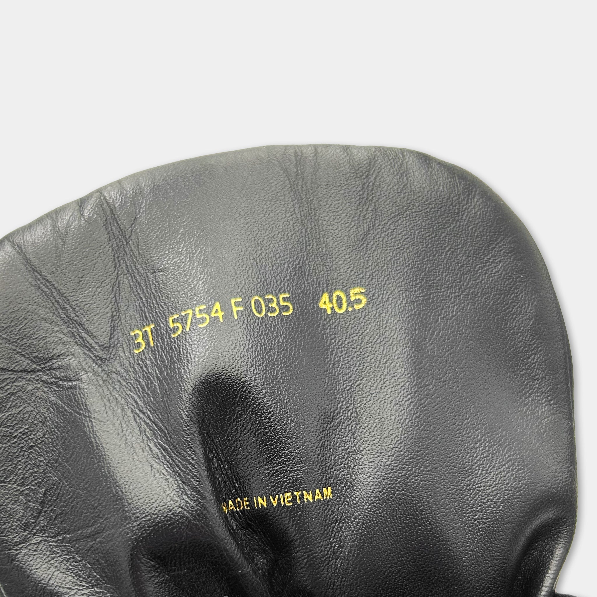 a close-up view of a black leather item, possibly a shoe or bag, with some text printed on it.