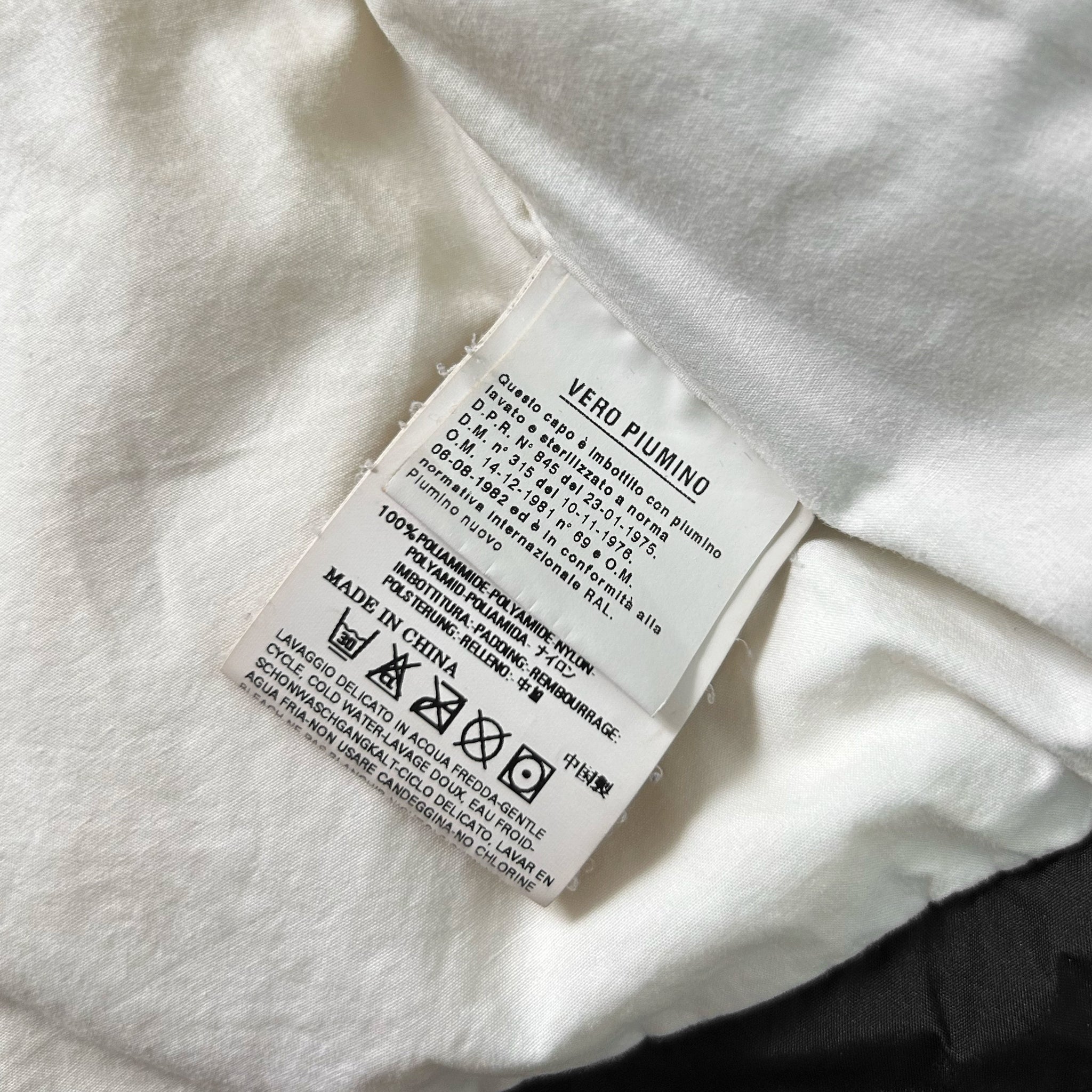 a close-up view of a white fabric label with text and symbols, likely providing information about the fabric or care instructions.