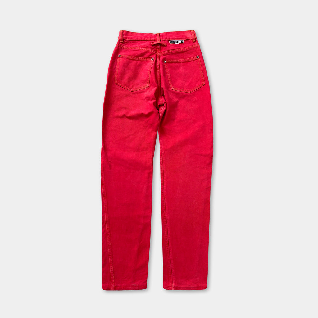 A pair of bright red, high-waisted jeans with a label on the waistband.