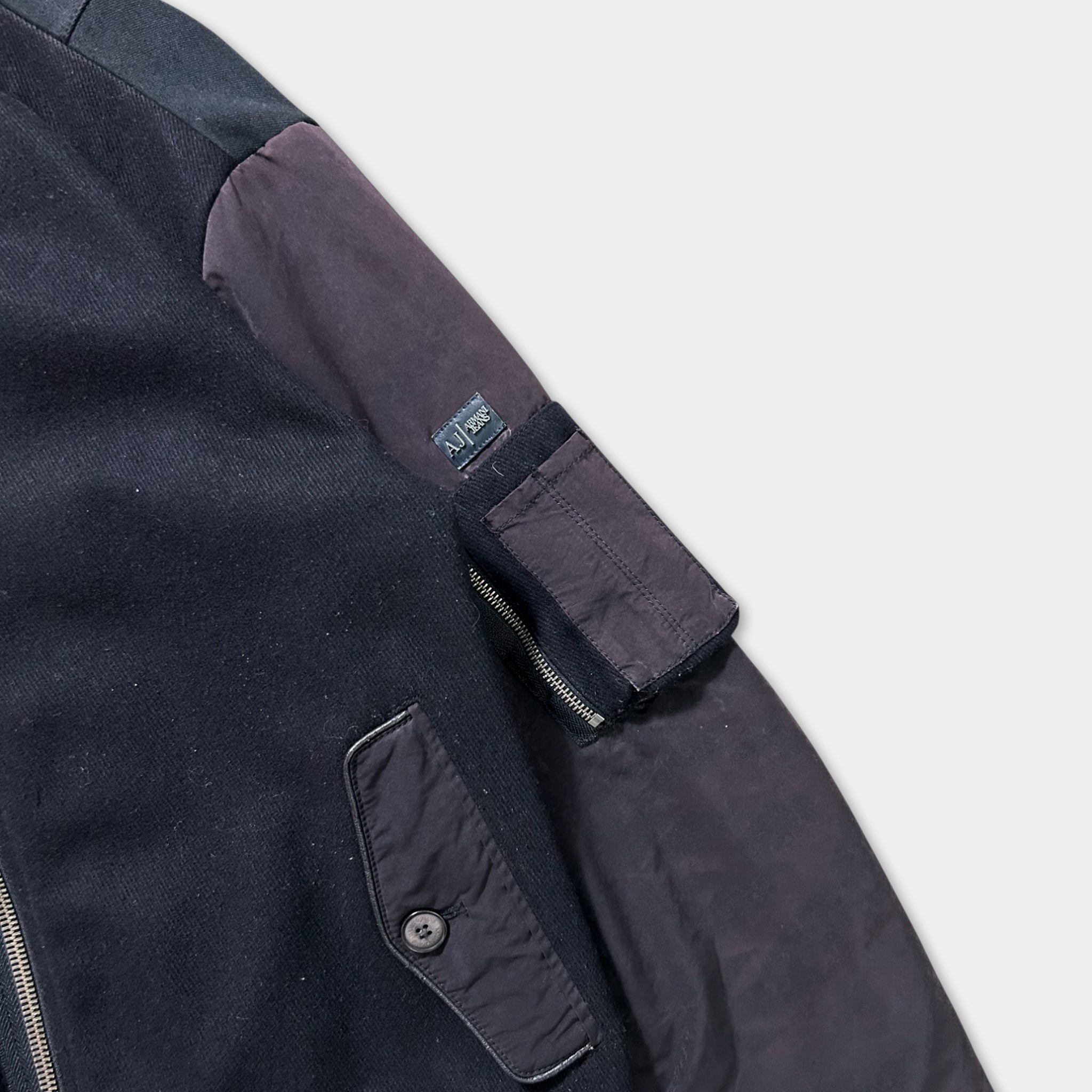 A close-up view of a dark-colored jacket with a zipper and a pocket on the left side.