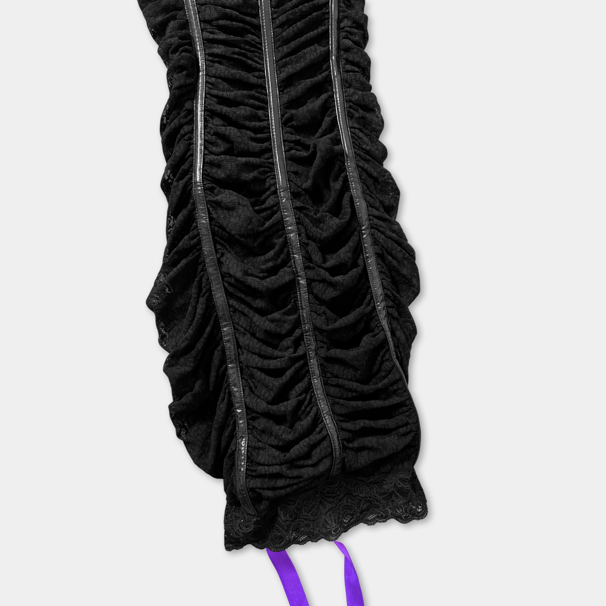 a close-up view of a black, ruched garment with a purple ribbon attached to the bottom.