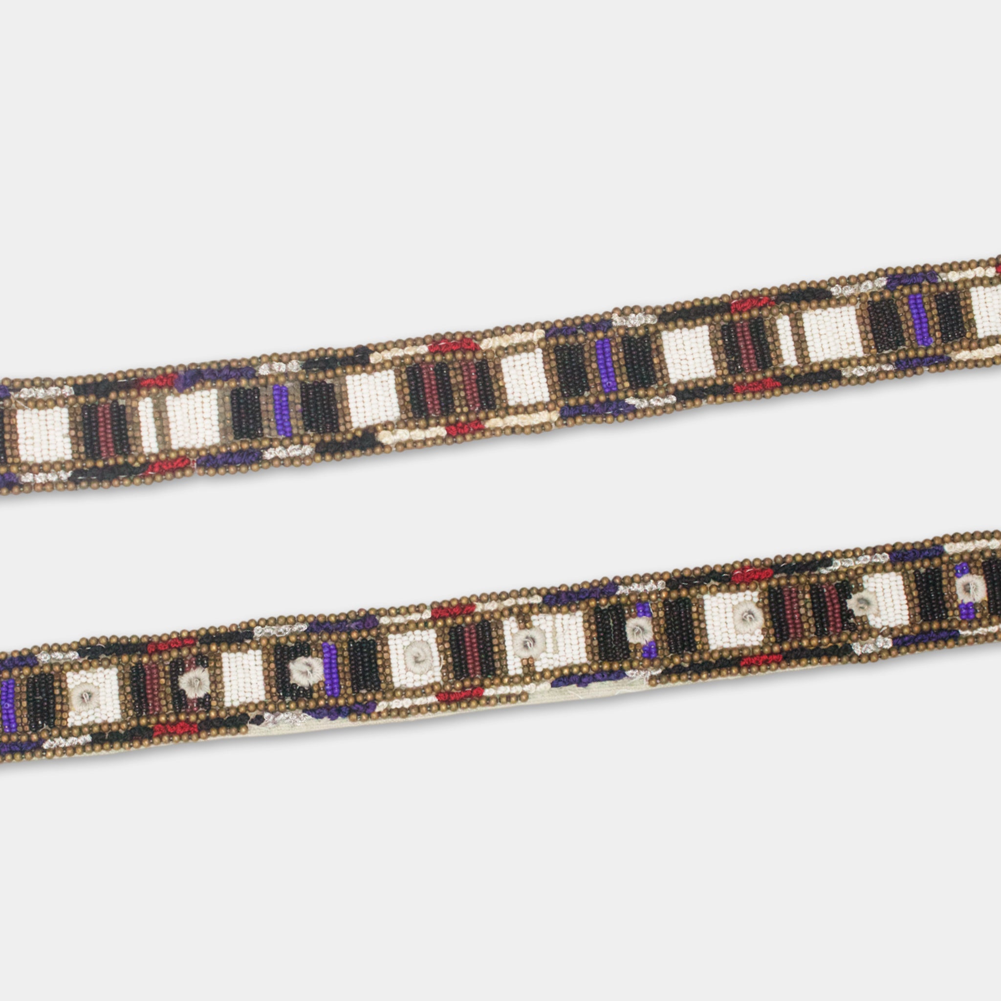 a decorative beaded belt with a repeating pattern of black, white, and red beads arranged in a diagonal line.