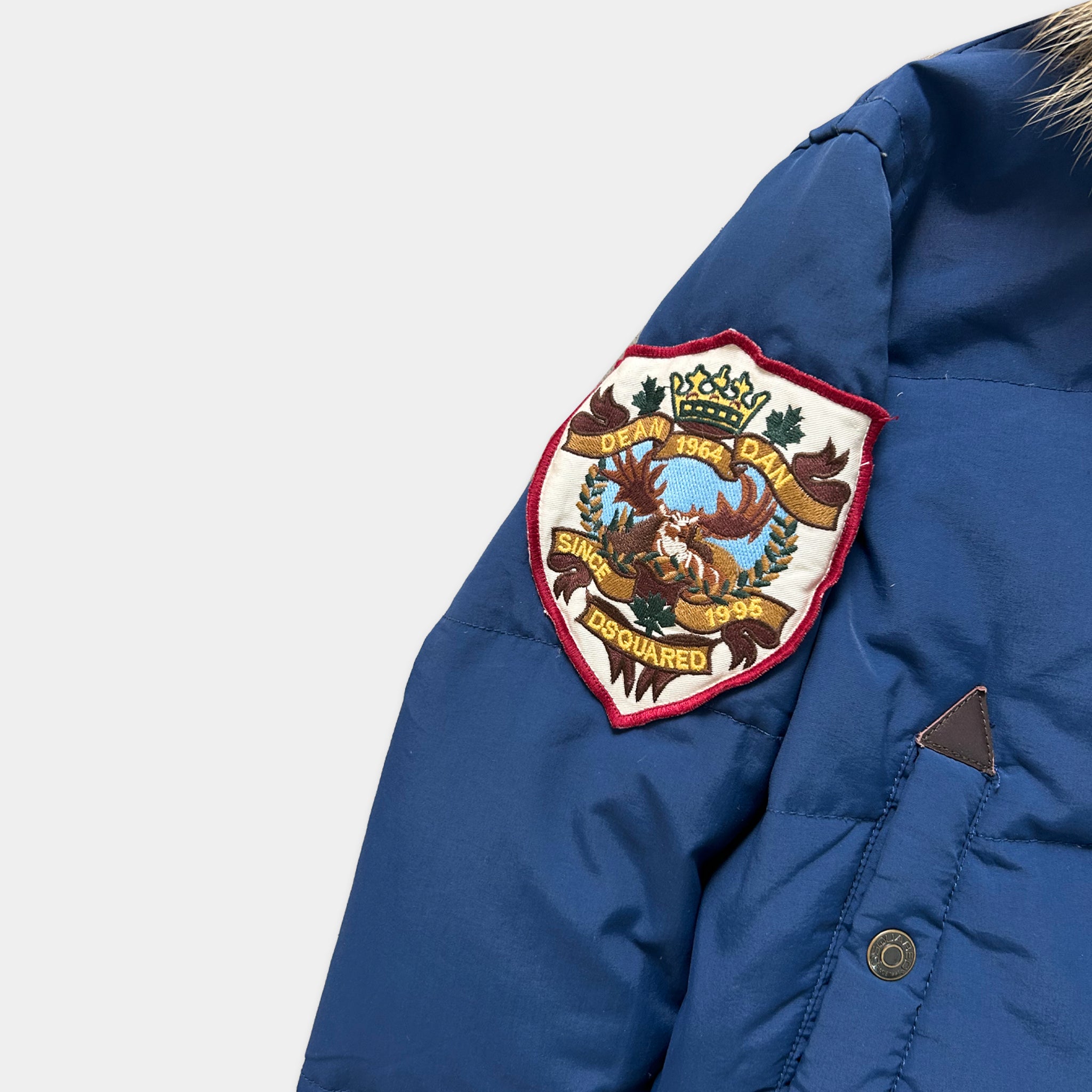 A close-up view of a blue jacket with a decorative patch on the left side of the chest.