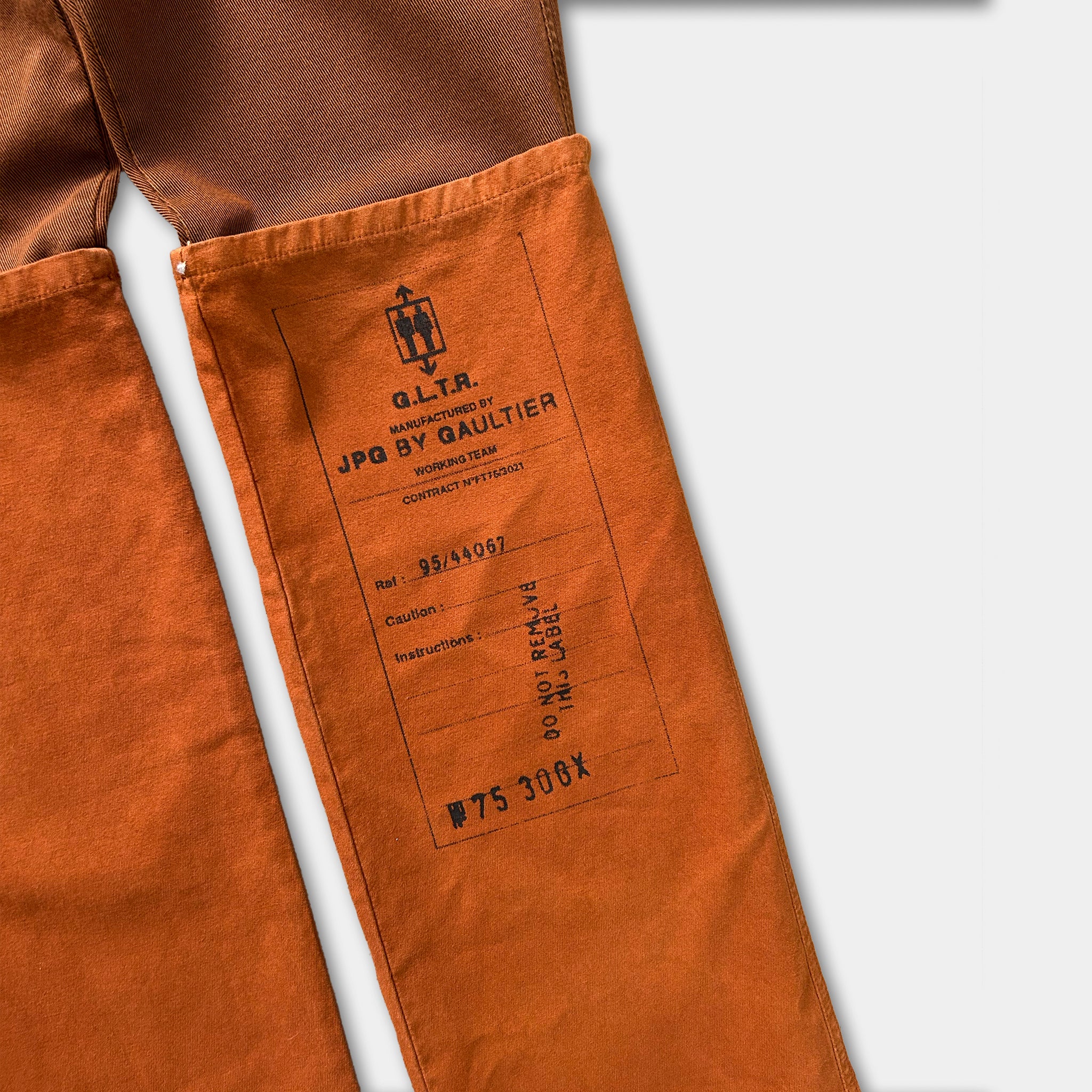 a pair of orange pants with a label or tag attached to the waistband. The label contains text and numbers, indicating the pants are from a specific brand or model.