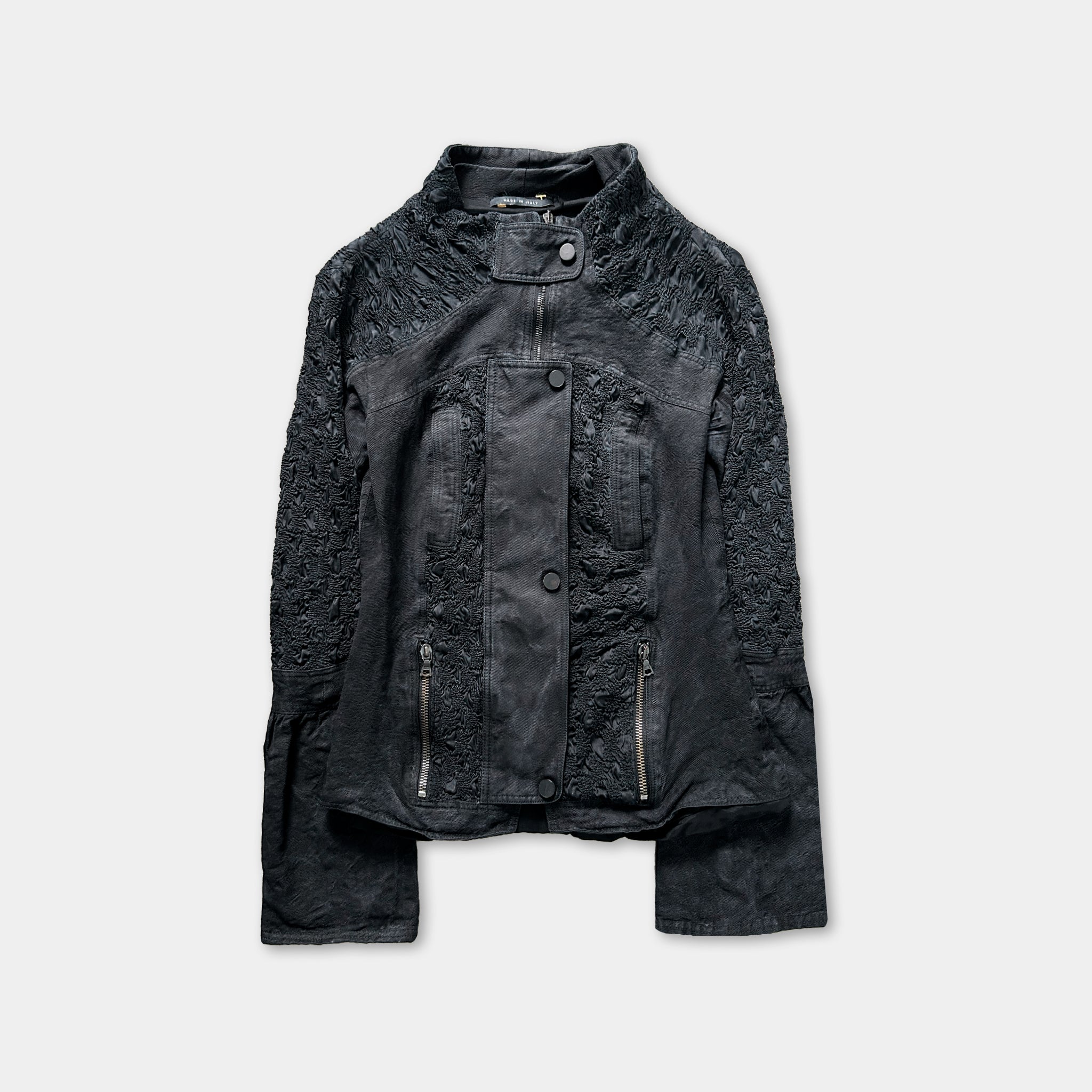 A black leather jacket with intricate embroidered details and multiple zippers.