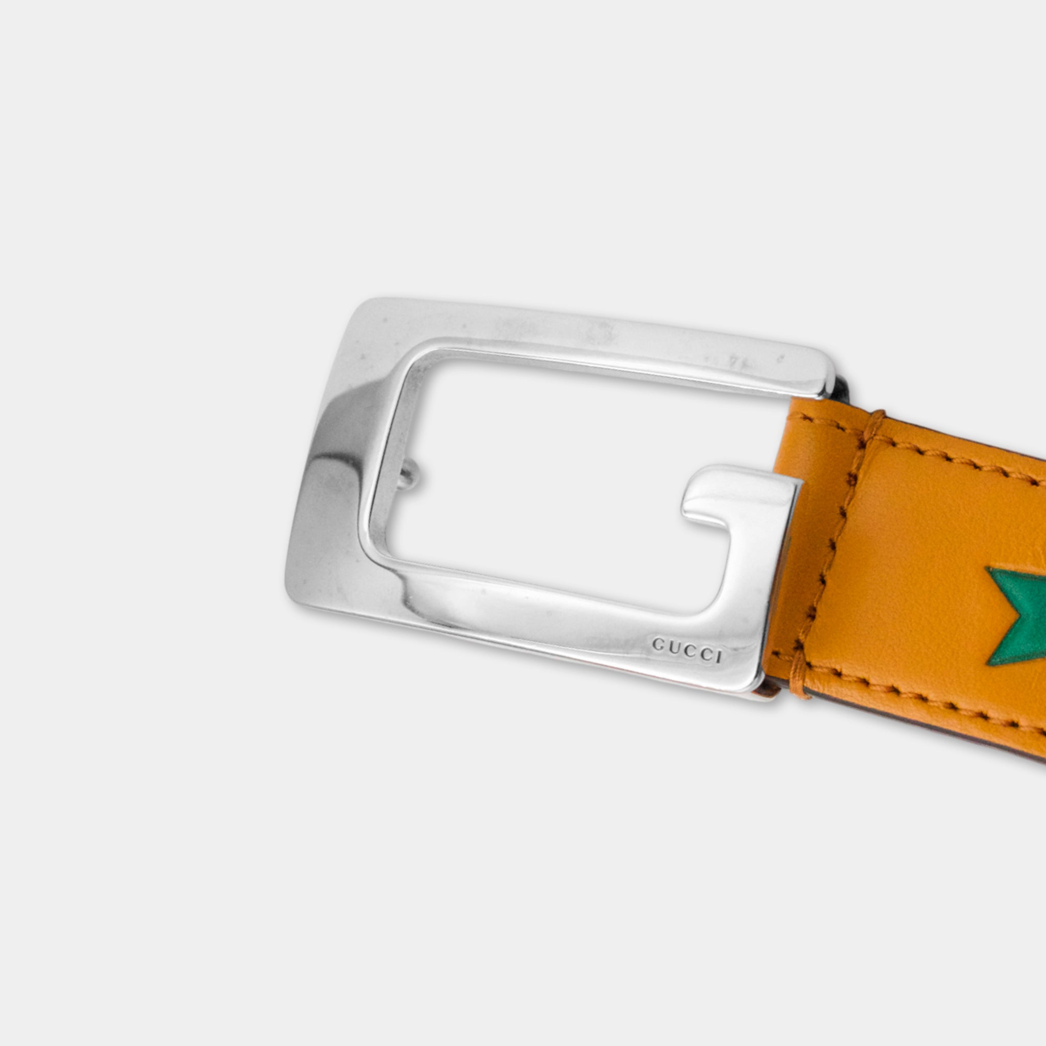 A close-up view of a leather belt buckle with a metal frame and a green star-shaped design on the leather strap.