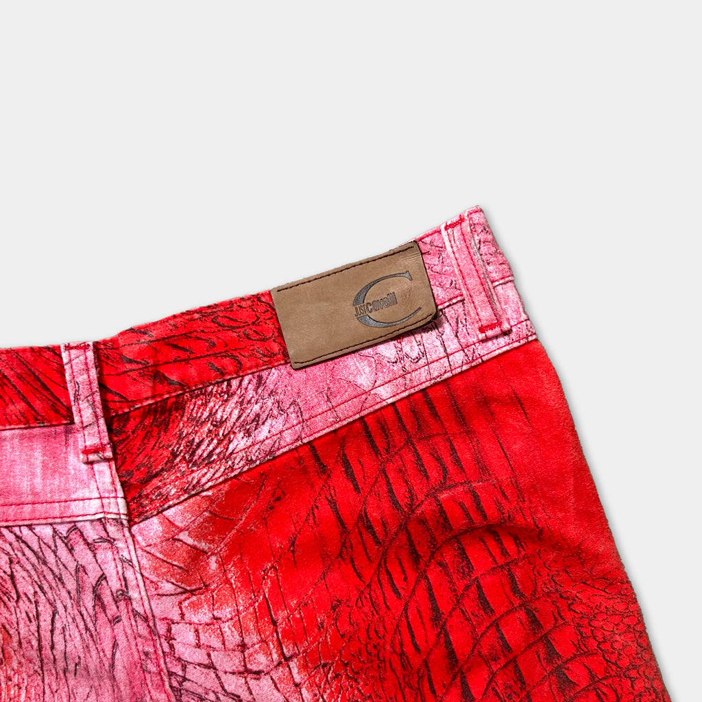 A close-up view of a pair of red pants with a brown leather patch on the waistband.