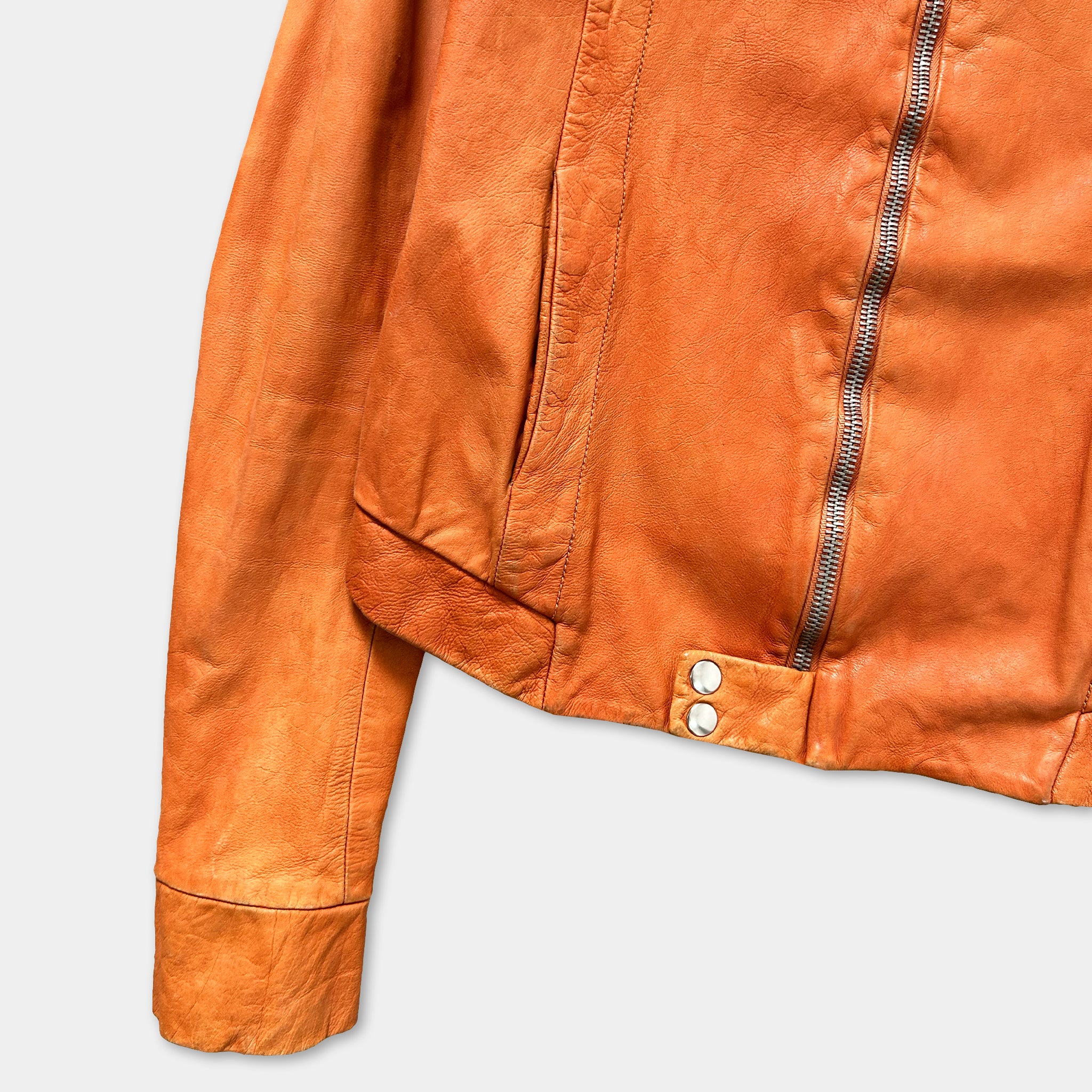 a close-up view of a brown leather jacket with a zipper and buttons.