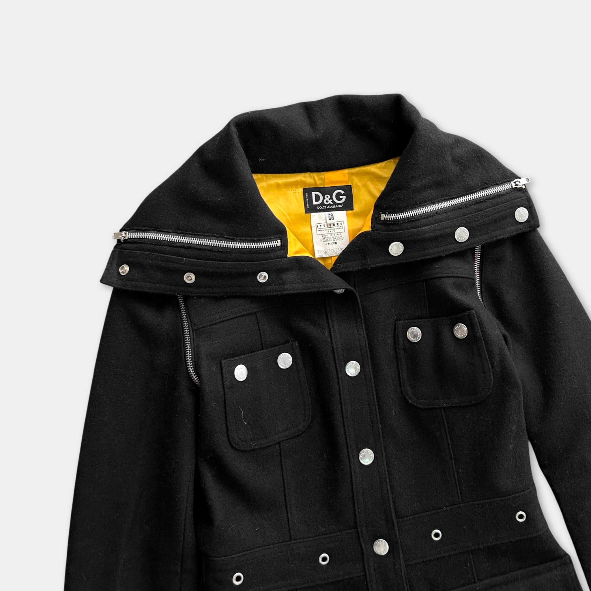 A black jacket with a yellow lining and multiple zippers, featuring a D&G logo on the chest.