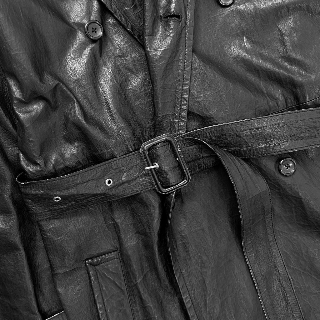 A close-up view of a black leather jacket, focusing on the belt and buttons.