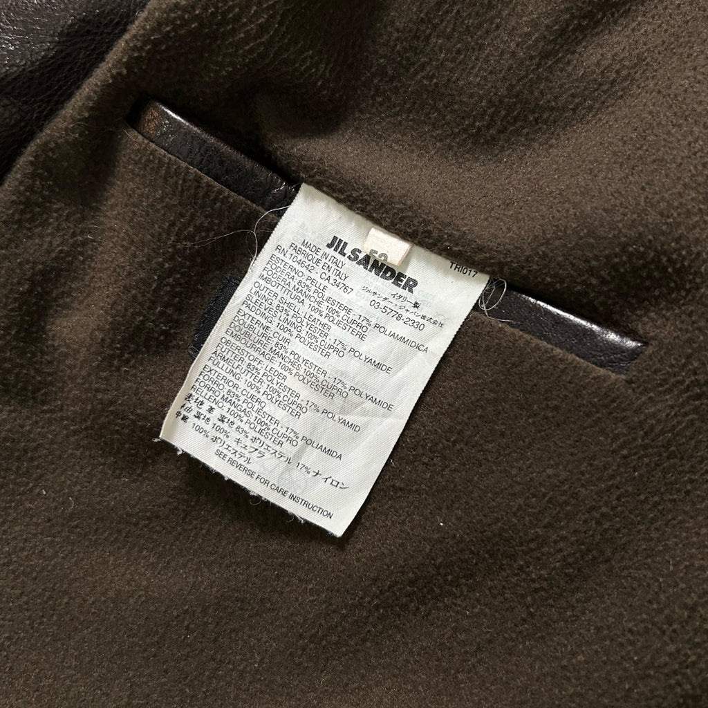 a close-up view of a label or tag attached to a piece of clothing, possibly a jacket or coat, with a brown fabric background.