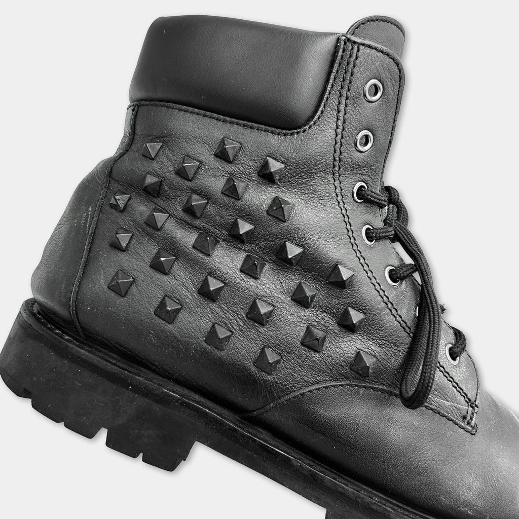 A close-up of a black leather boot with a distinctive studded design.