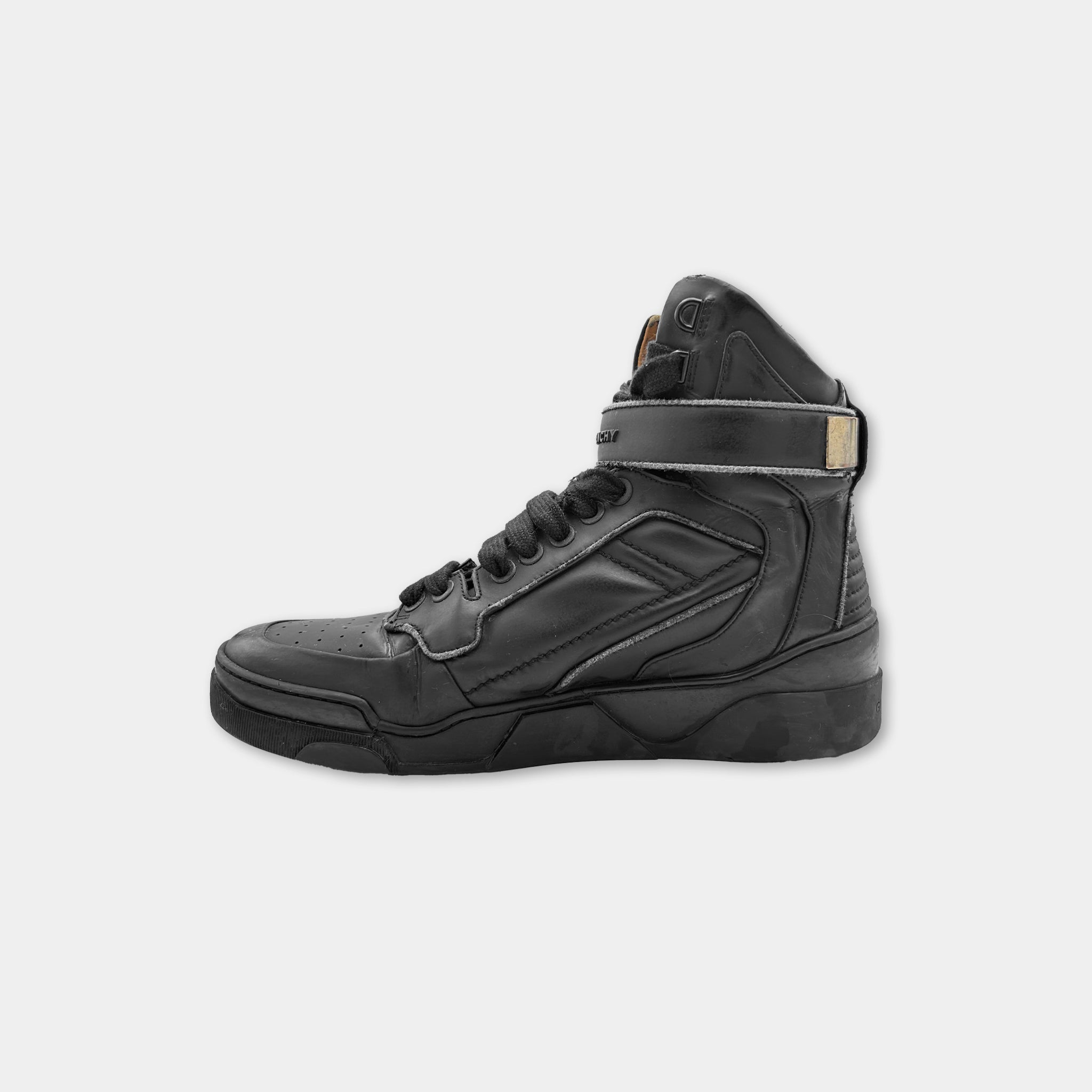 A black high-top sneaker with a distinctive design and a black strap.