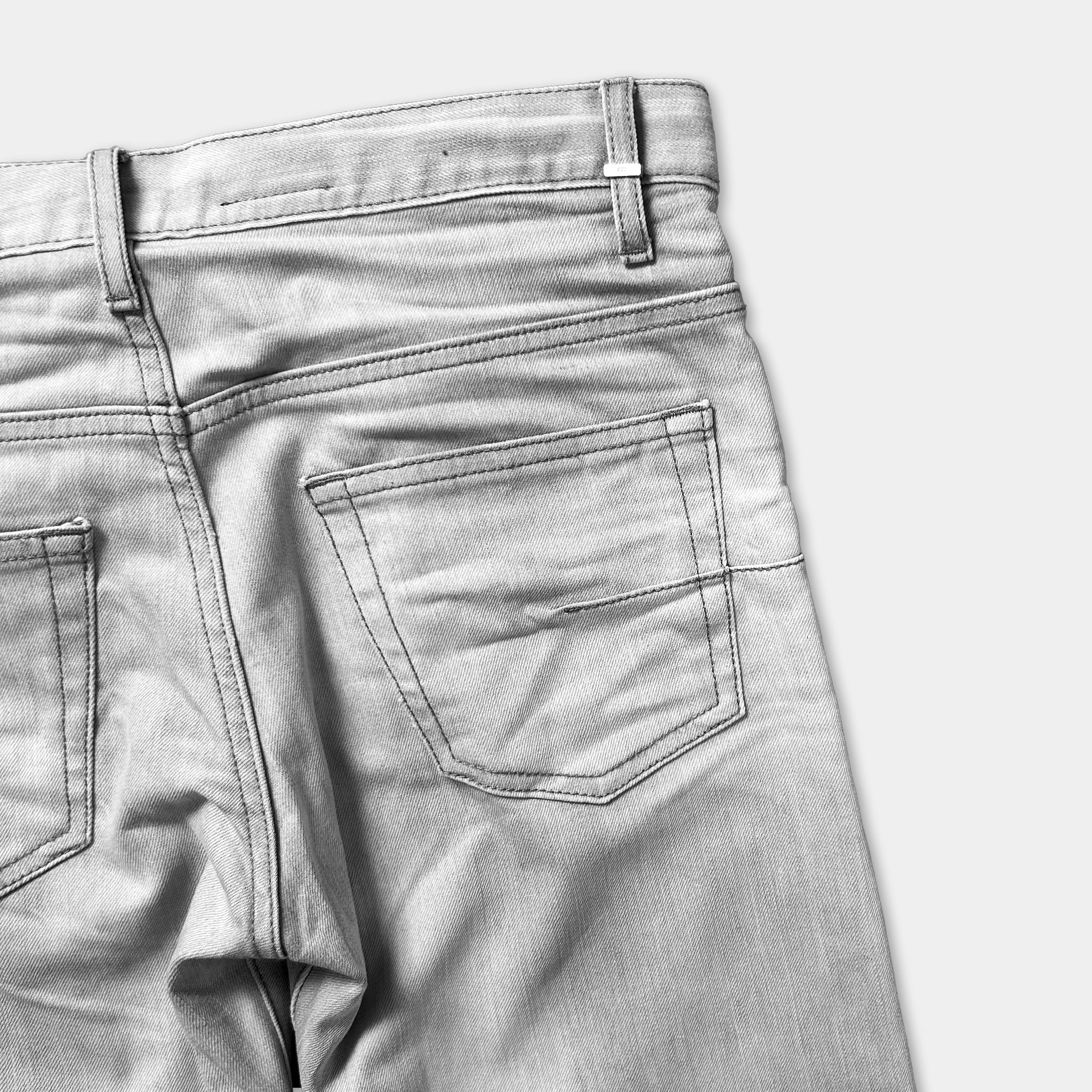 A close-up view of the back of a pair of gray jeans, showing the pocket and the waistband.
