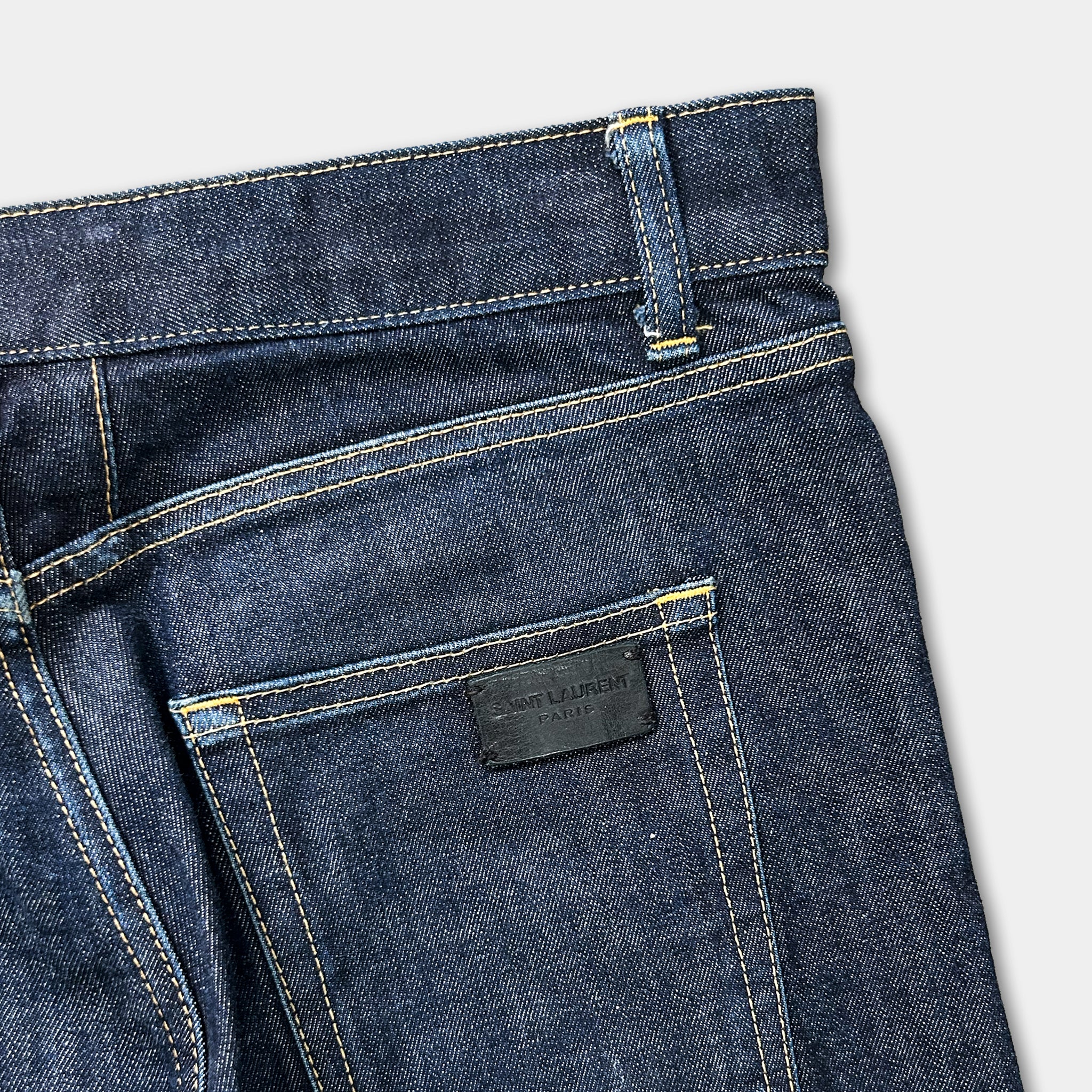 A close-up view of a pair of blue jeans with a black label on the pocket.