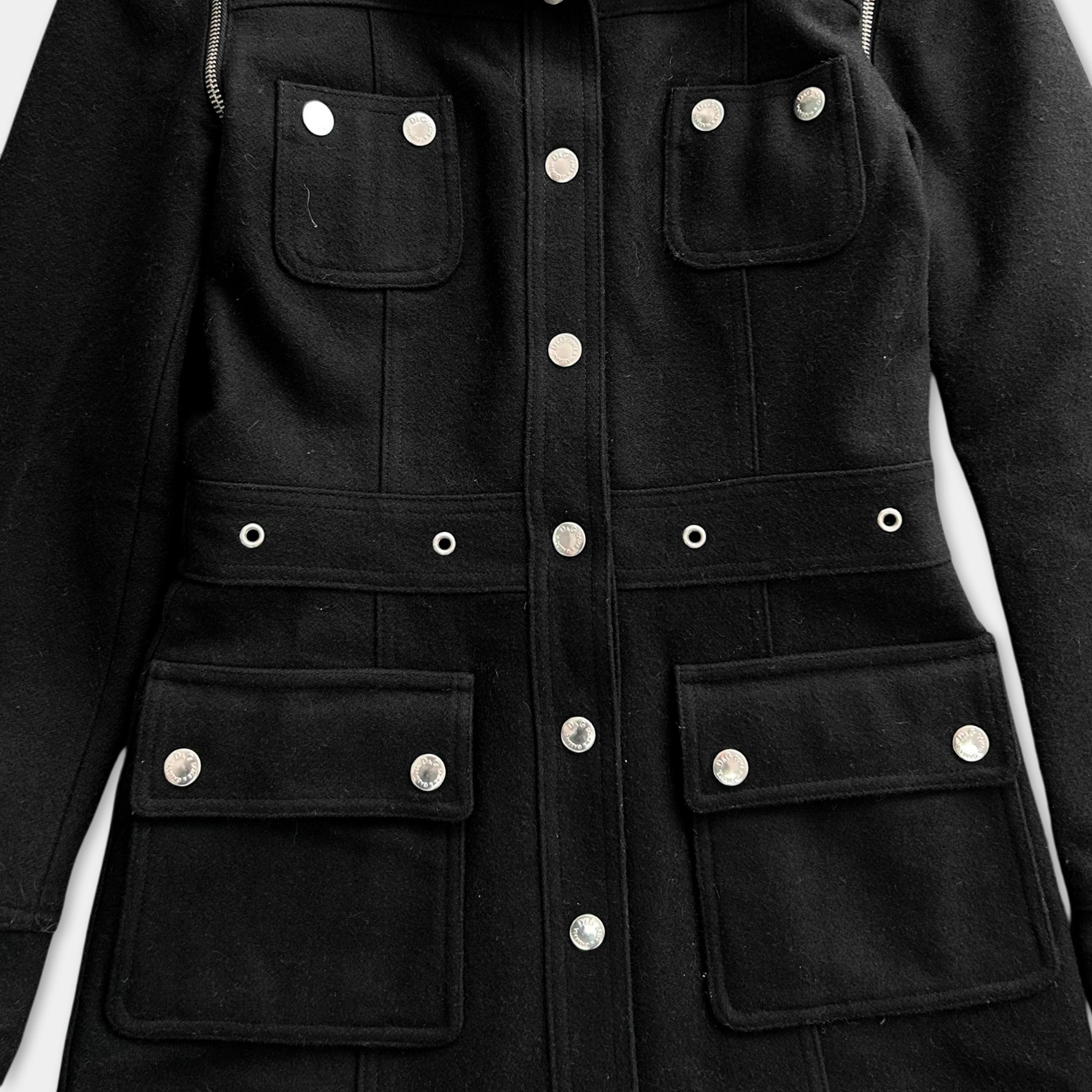 A close-up view of a black coat with multiple pockets and buttons.