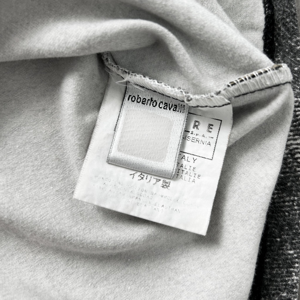 A close-up black and white image of a fabric label with text and logos, including the brand name and country of origin.