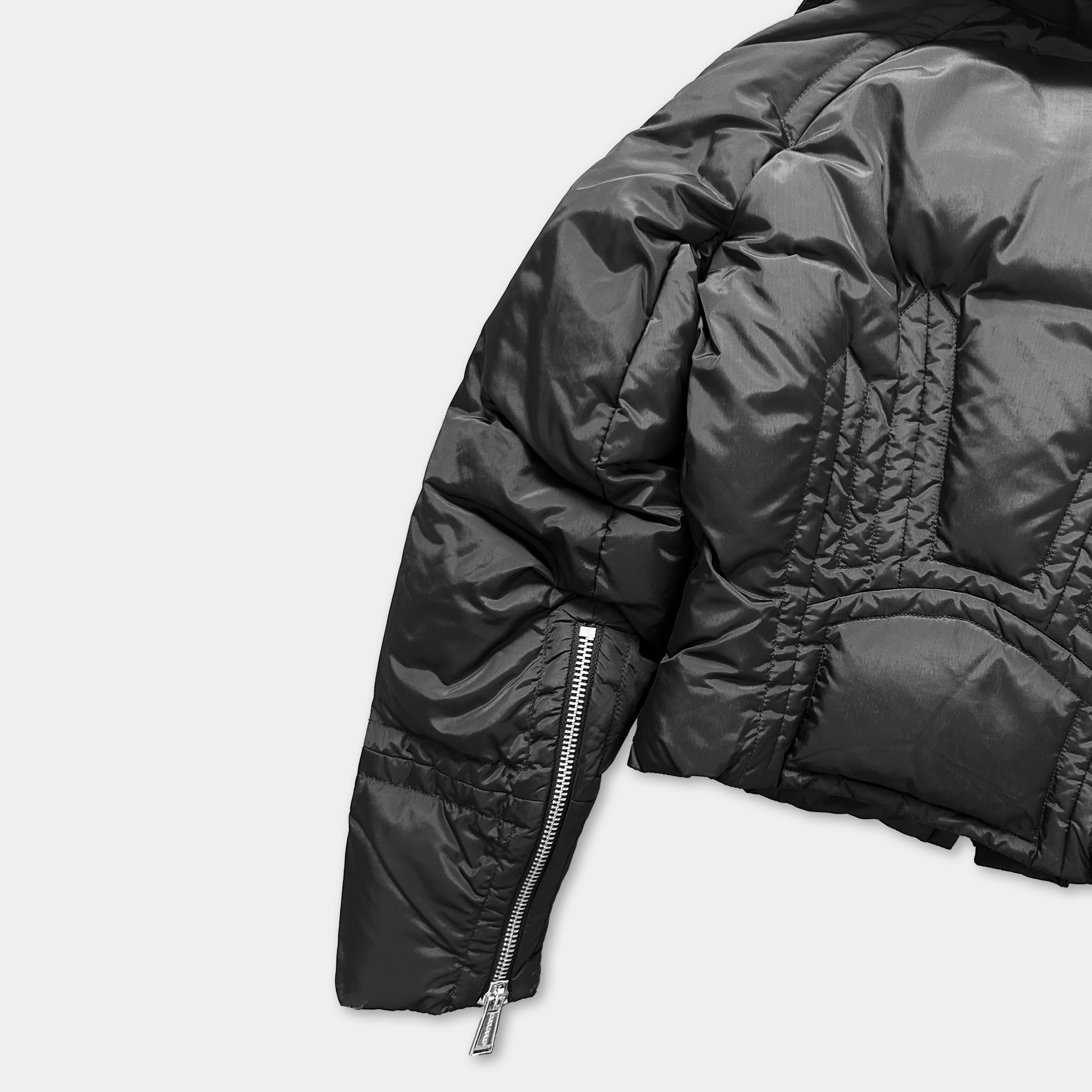 A close-up view of a black padded jacket with a zipper detail on the left side.