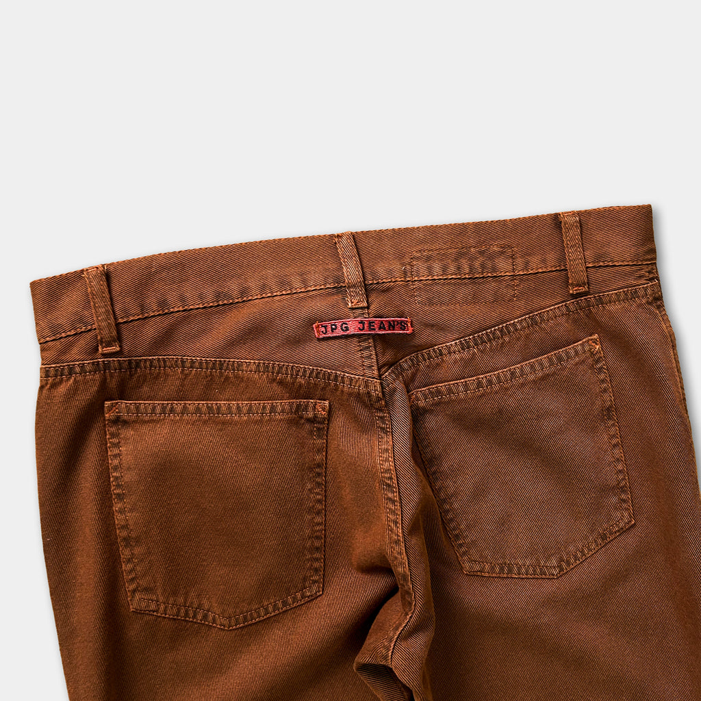 A pair of brown, well-worn jeans with a red tag on the waistband.