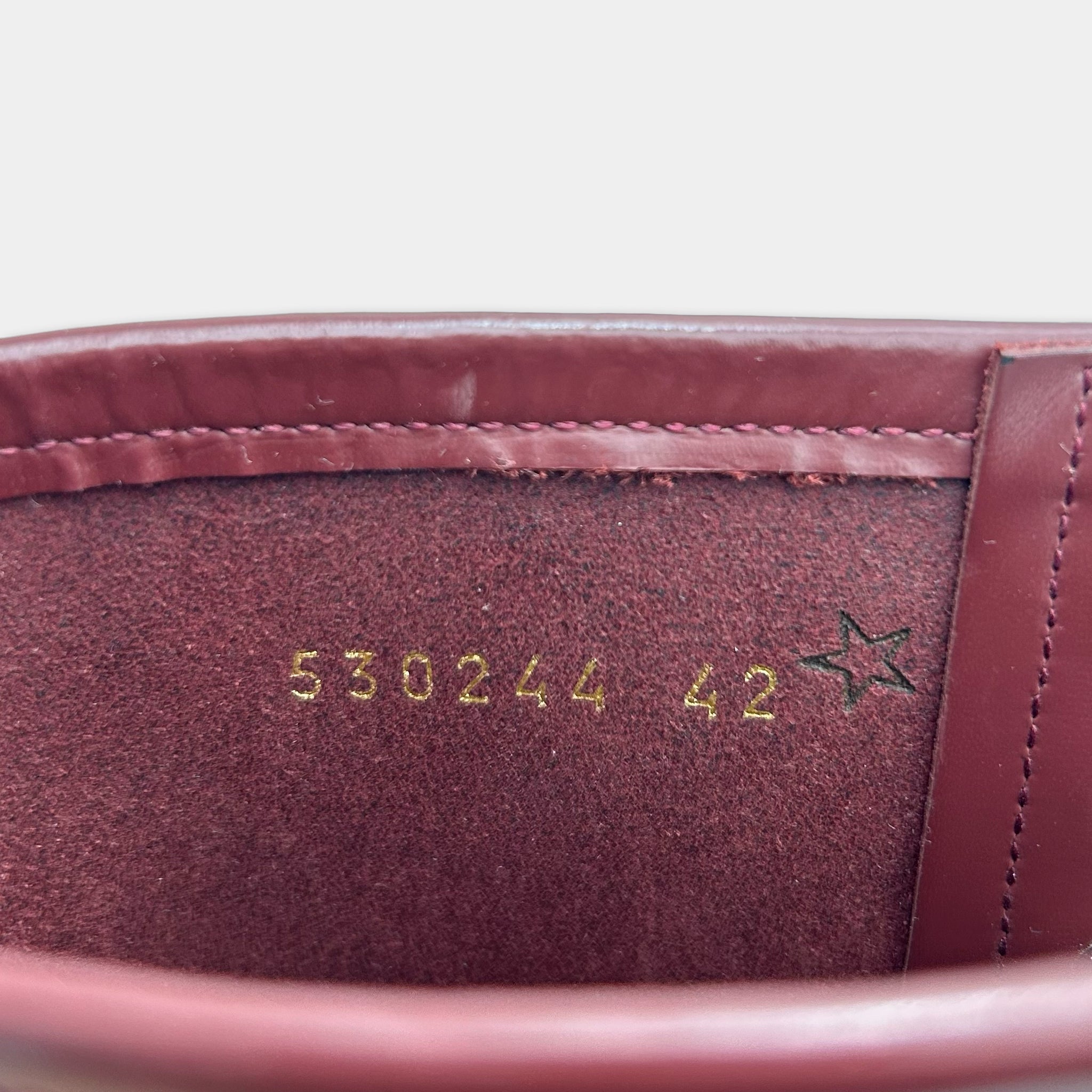 the inside of a red leather boot, with the number "5302444" and a star symbol printed on the leather.