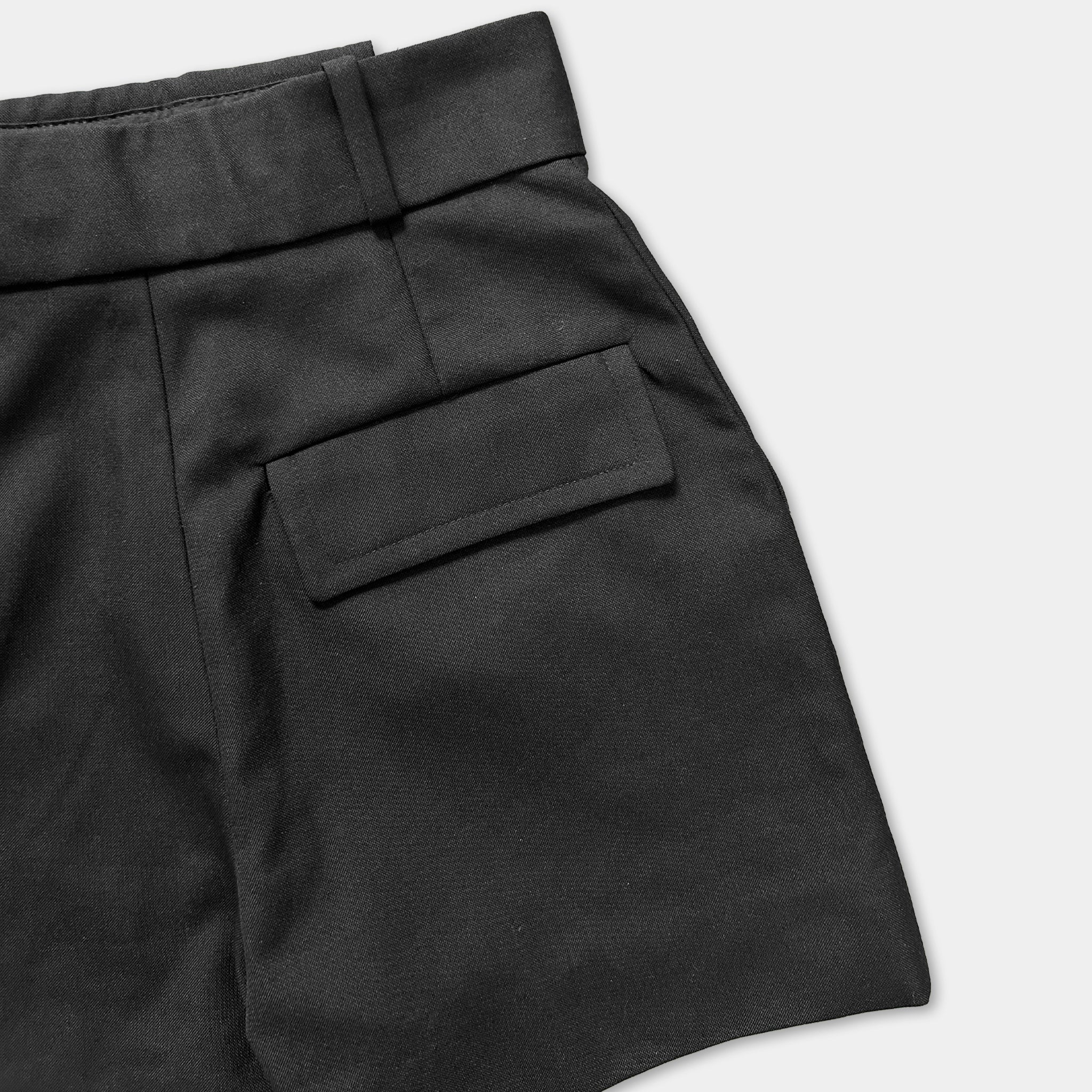 A close-up view of a pair of black shorts with a pocket on the front.