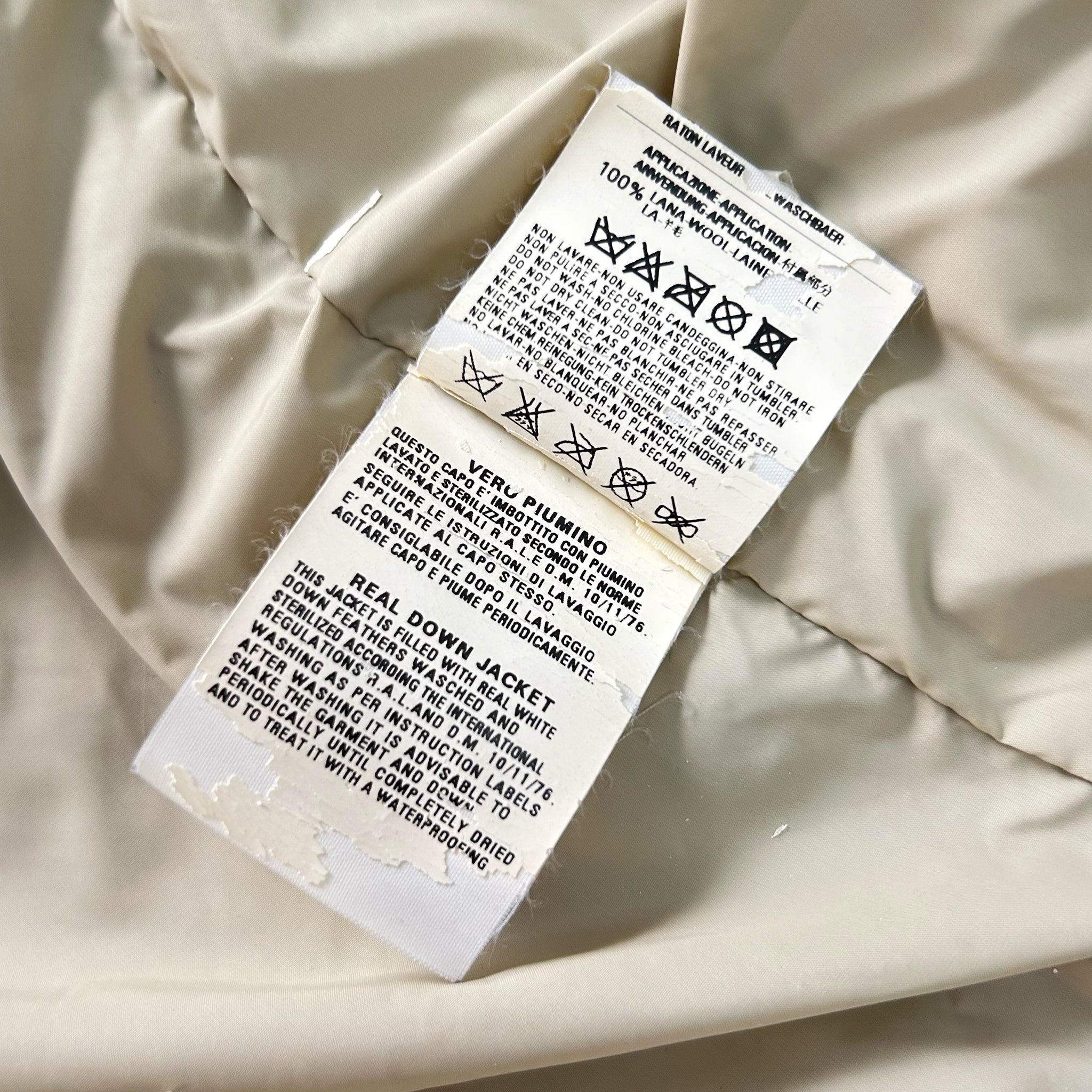 a close-up of a white fabric, possibly a jacket or blanket, with a label attached to it. The label appears to contain instructions or information about the fabric, such as care instructions or the material's properties.