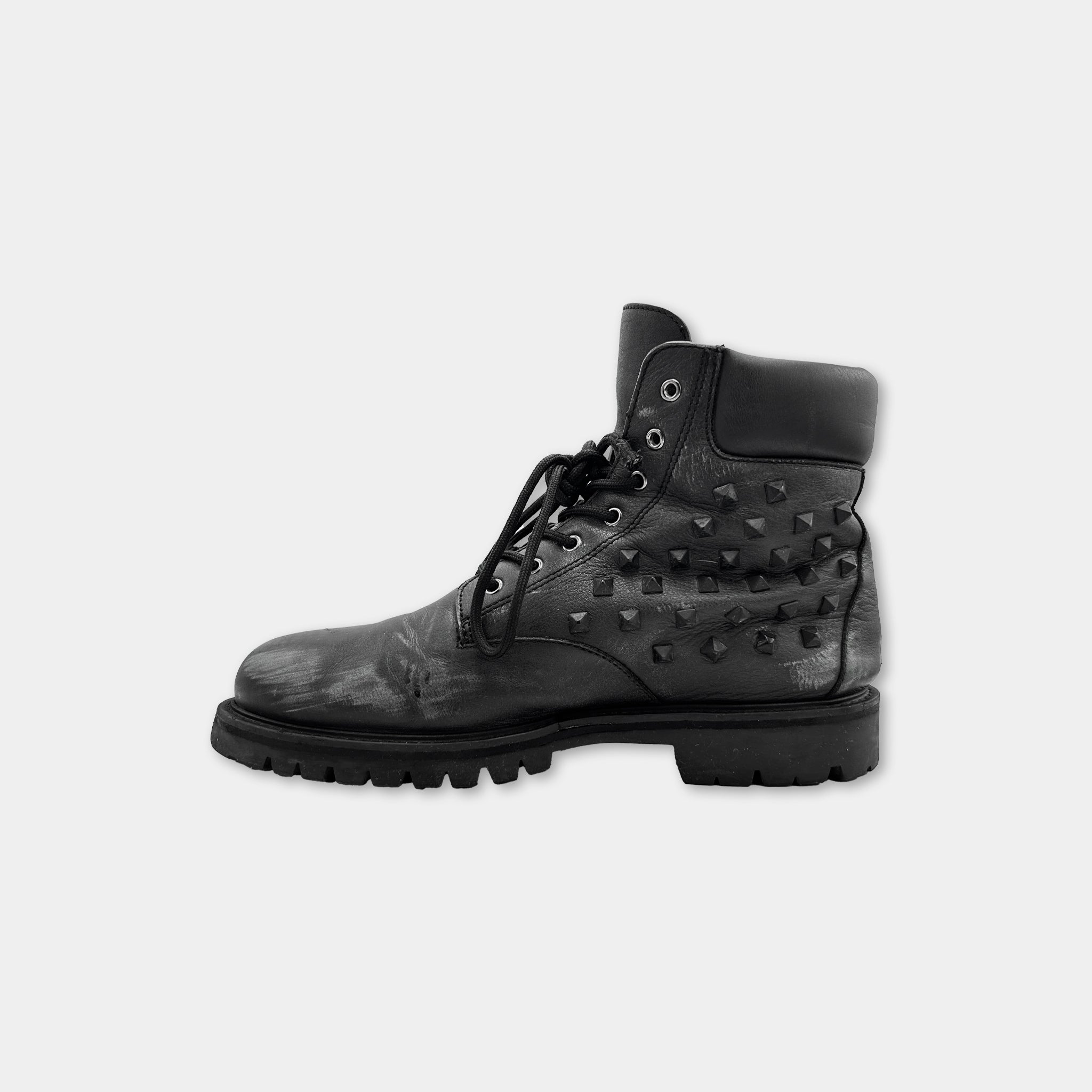 A black leather boot with studded details and a lace-up closure.