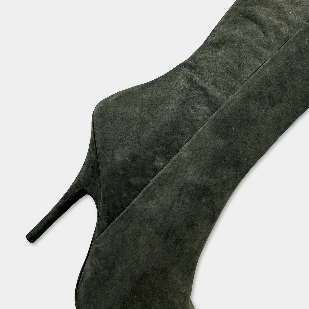 A close-up view of a dark green suede high-heeled boot.