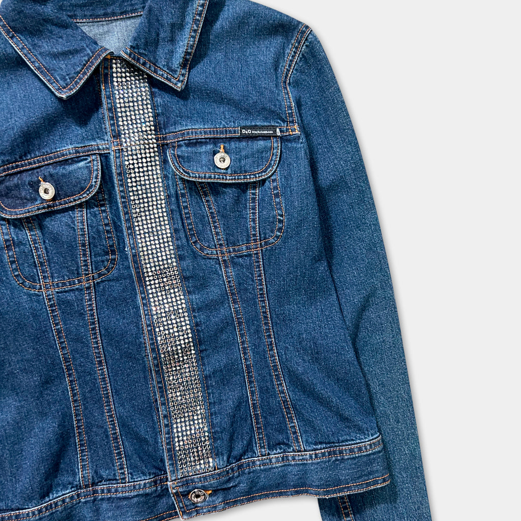 A close-up view of a blue denim jacket with a silver rhinestone embellishment on the left side.