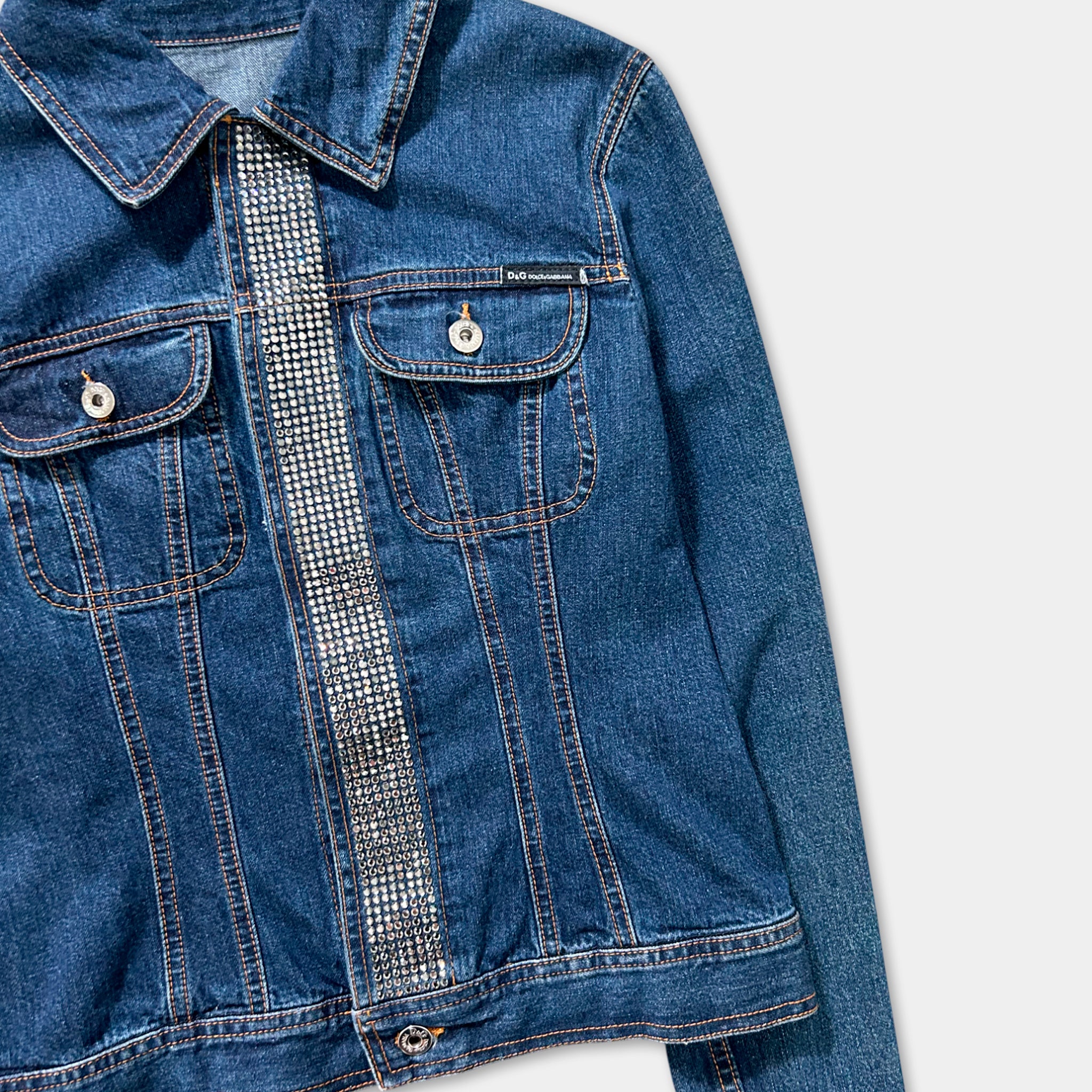 A close-up view of a blue denim jacket with a silver rhinestone embellishment on the left side.