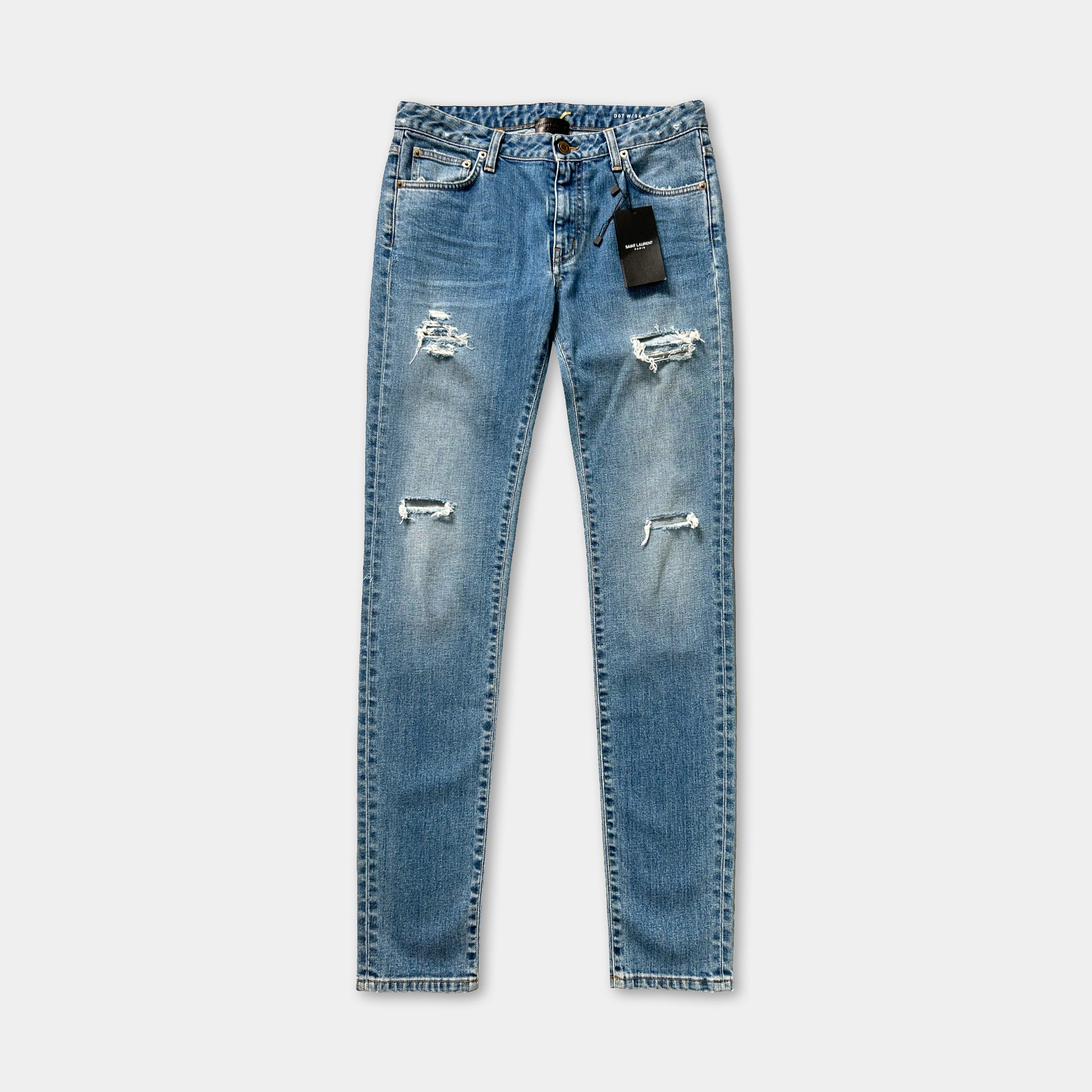 A pair of blue jeans with visible holes and a tag attached to the waistband.