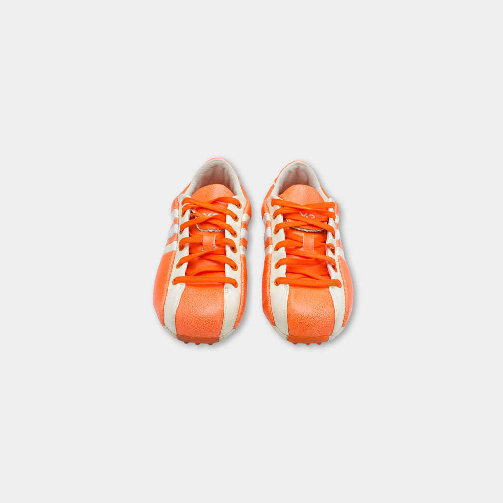 A pair of orange and white sneakers against a white background.