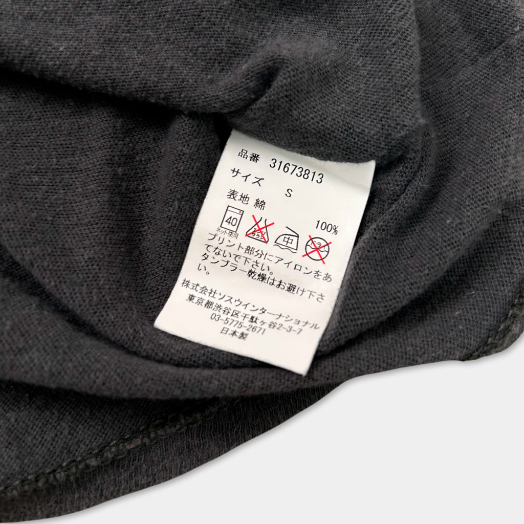 a close-up view of a black fabric, possibly a sweater or garment, with a white label attached to it. The label contains text in Japanese and English, along with some symbols and numbers, likely indicating the garment's size, care instructions, or other relevant information.