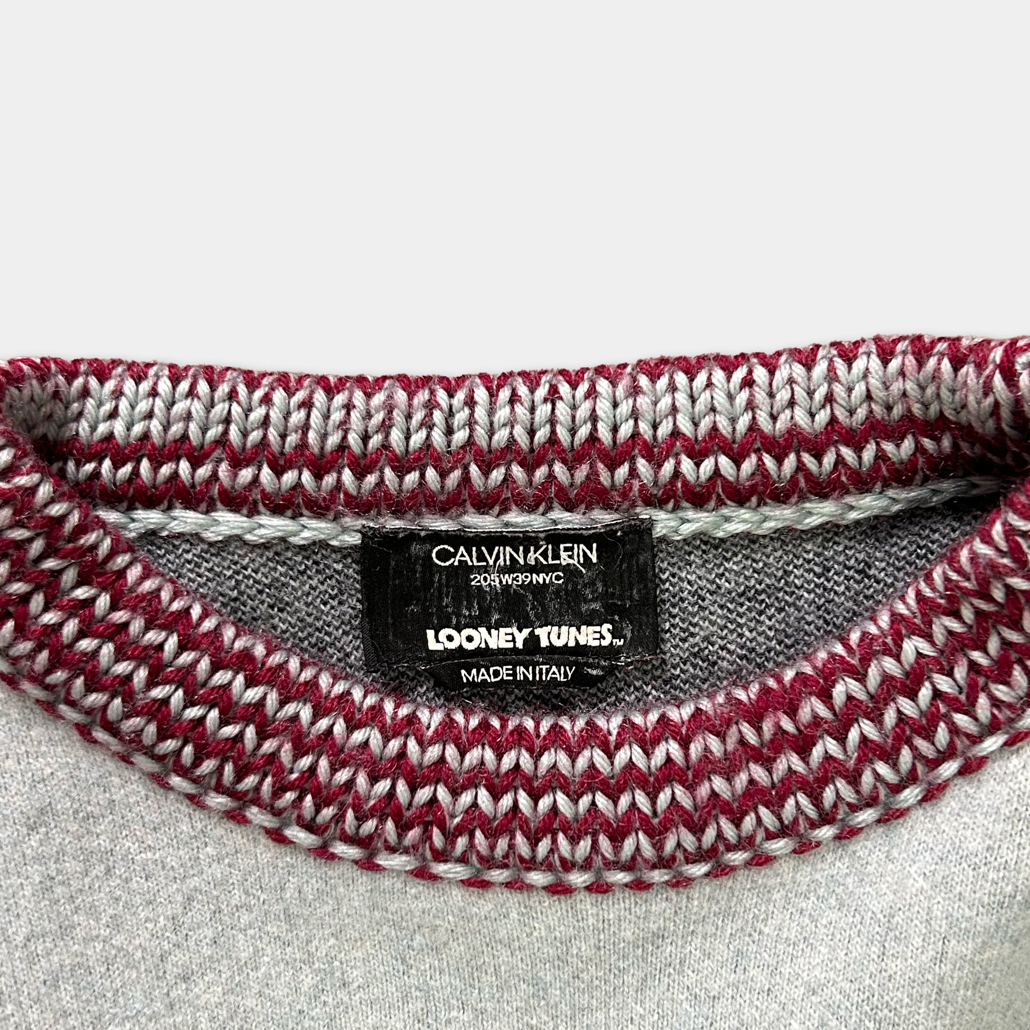 A close-up view of a knitted sweater collar with a label indicating the brand and product information.