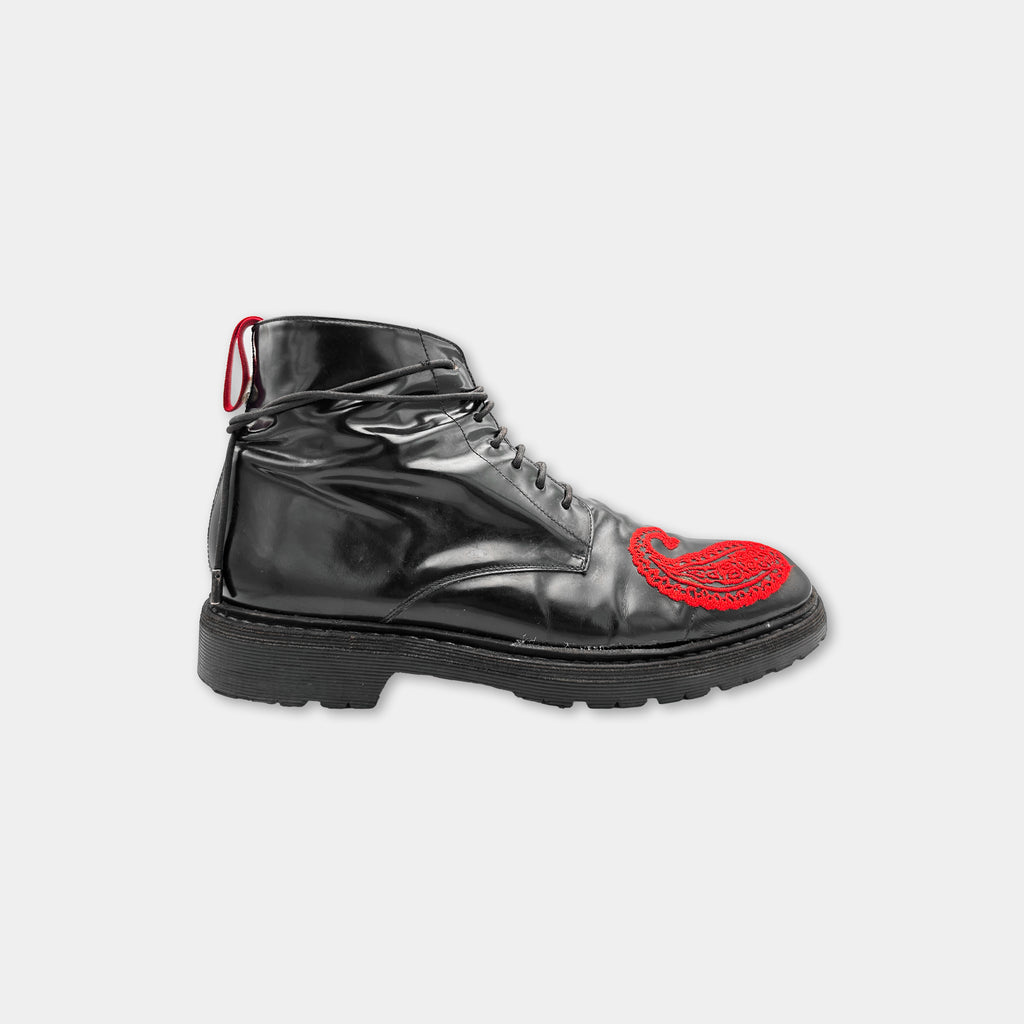 A black leather boot with a red embroidered design on the side.