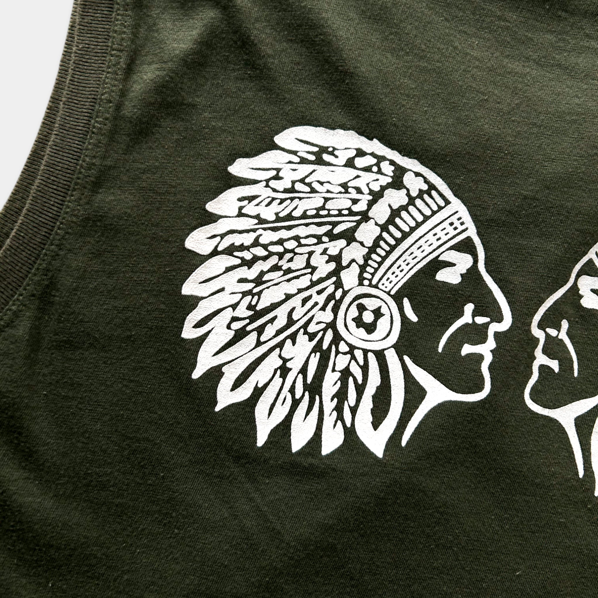 a close-up view of a dark green t-shirt with a white graphic design depicting a Native American headdress.