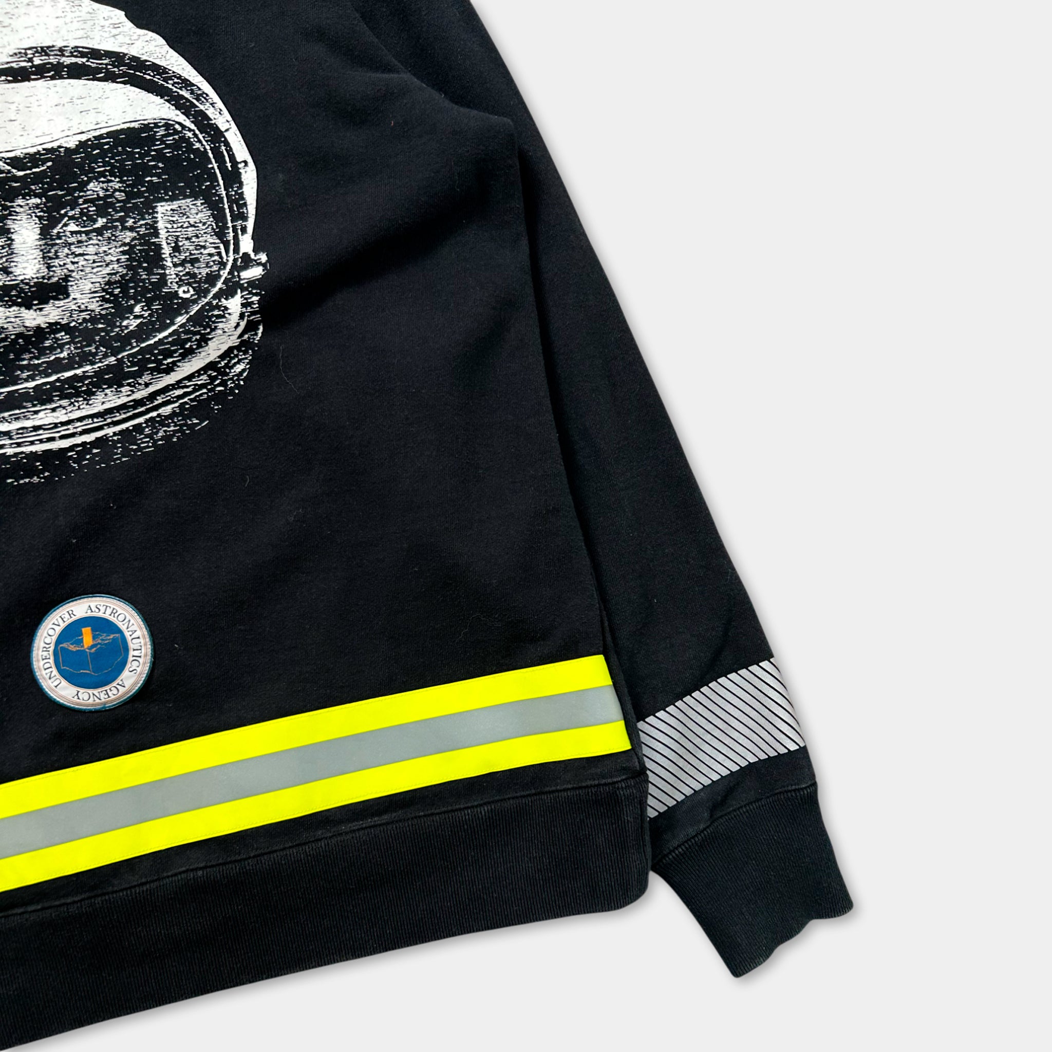 a black sweatshirt with a white and yellow design featuring a helmet and a circular emblem.