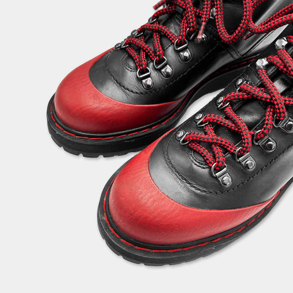 A pair of black and red leather boots with red laces and a red sole.